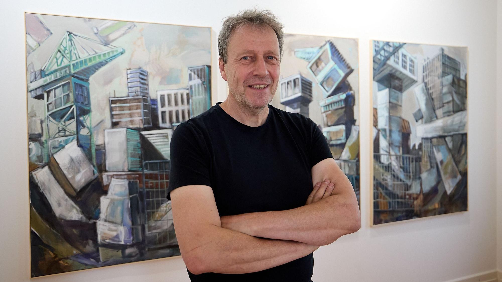 Klaus Tenner steht vor einer Reihe seiner Bilder.