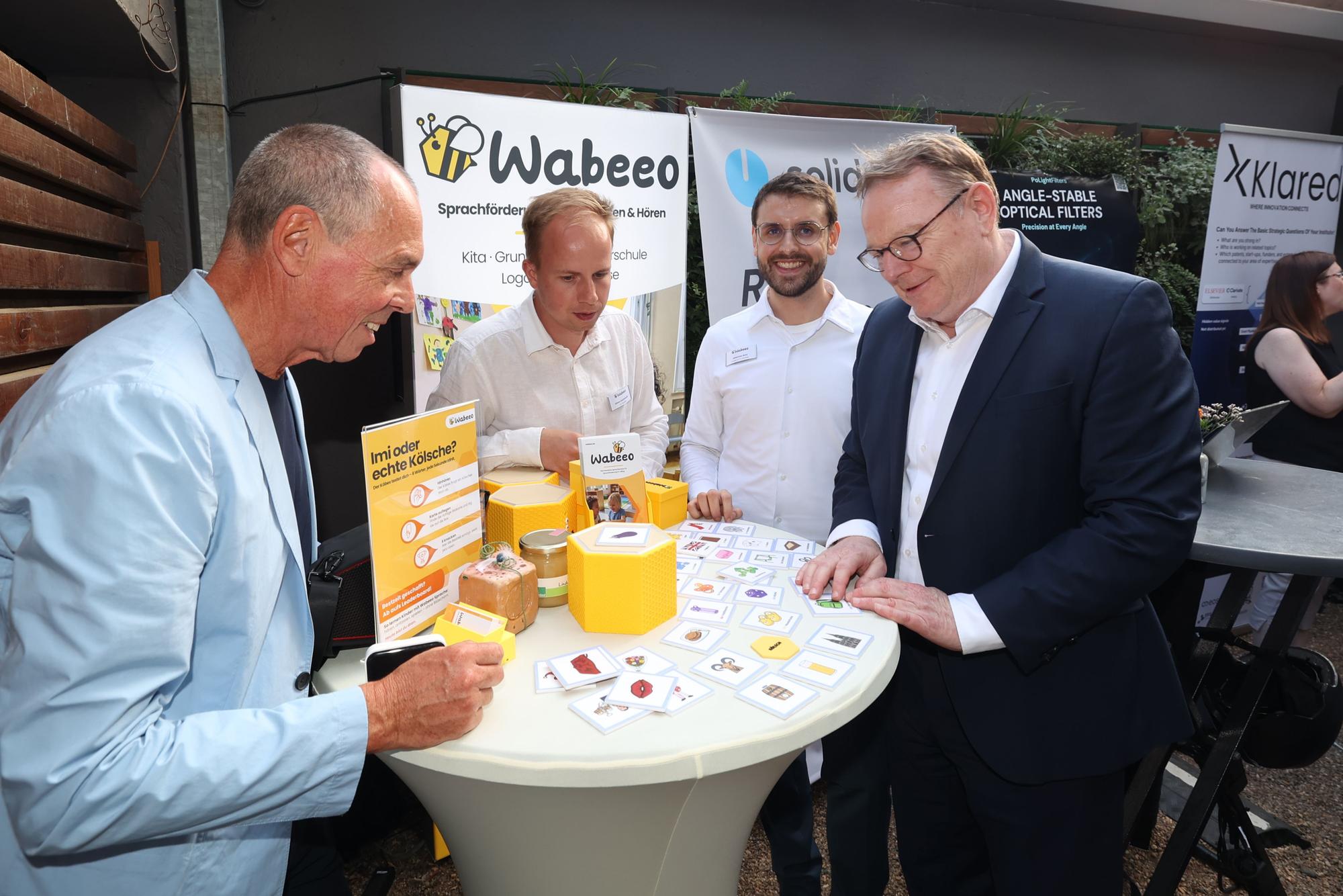 OB Torsten Burmester (r.) und Joachim Vranken von Web de Cologne (l.) lassen sich die Sprachlernbox des Kölner Start-ups Wabeeo zeigen. Entwickelt haben sie die Gründer Johannes Arnz und Simon Aschemeier.