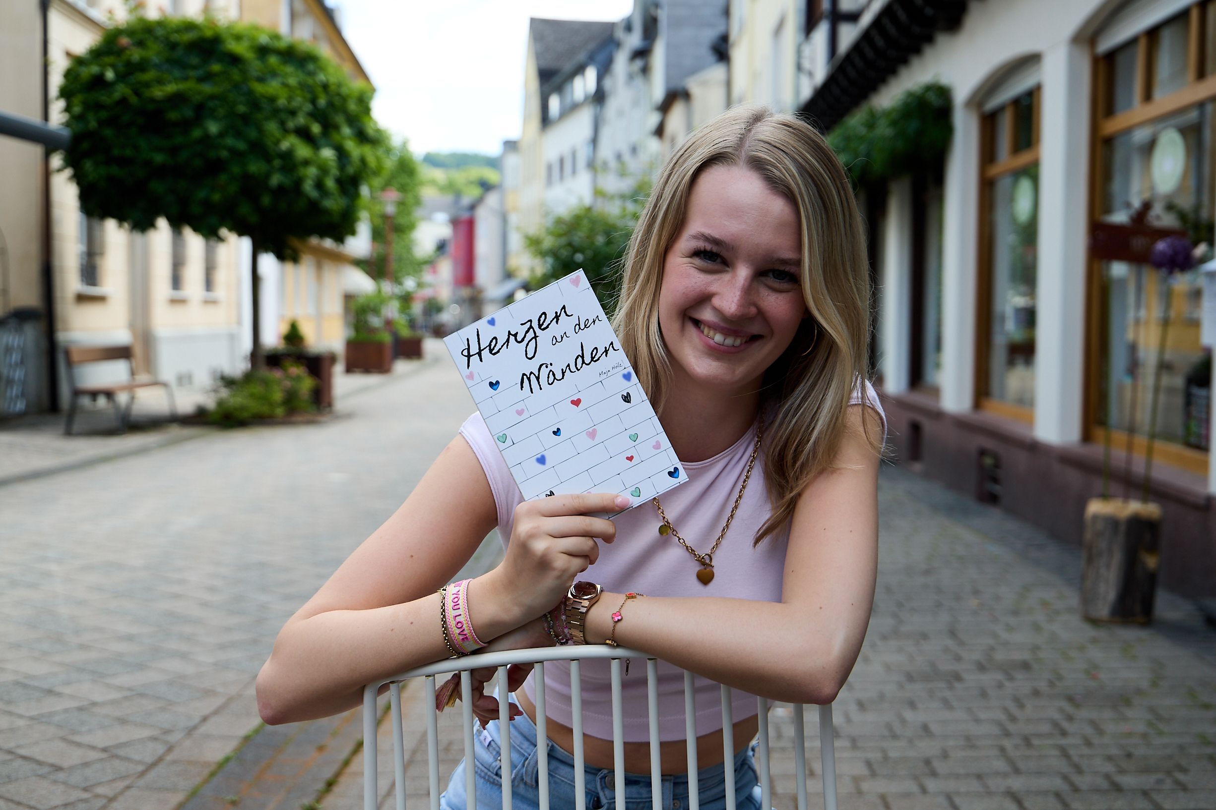 Maja Hölz steht in der Fußgängerzone und hält ihr Buch in den Händen.