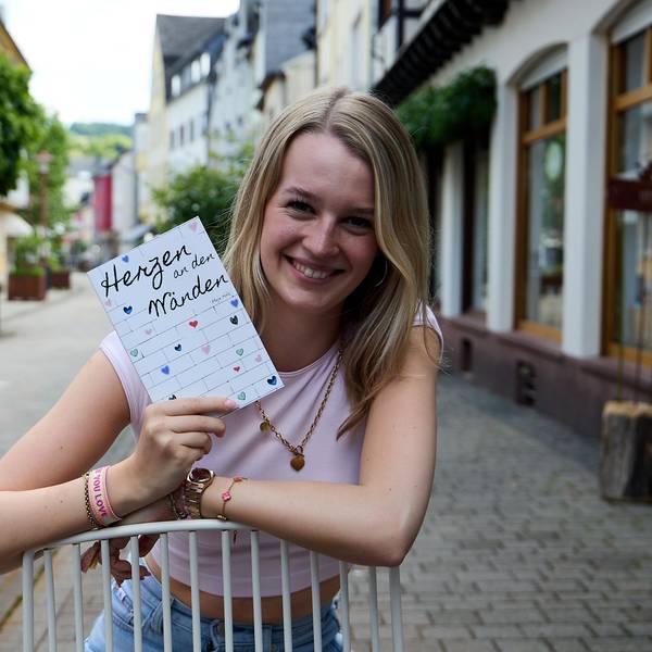 Maja Hölz steht in der Fußgängerzone und hält ihr Buch in den Händen.