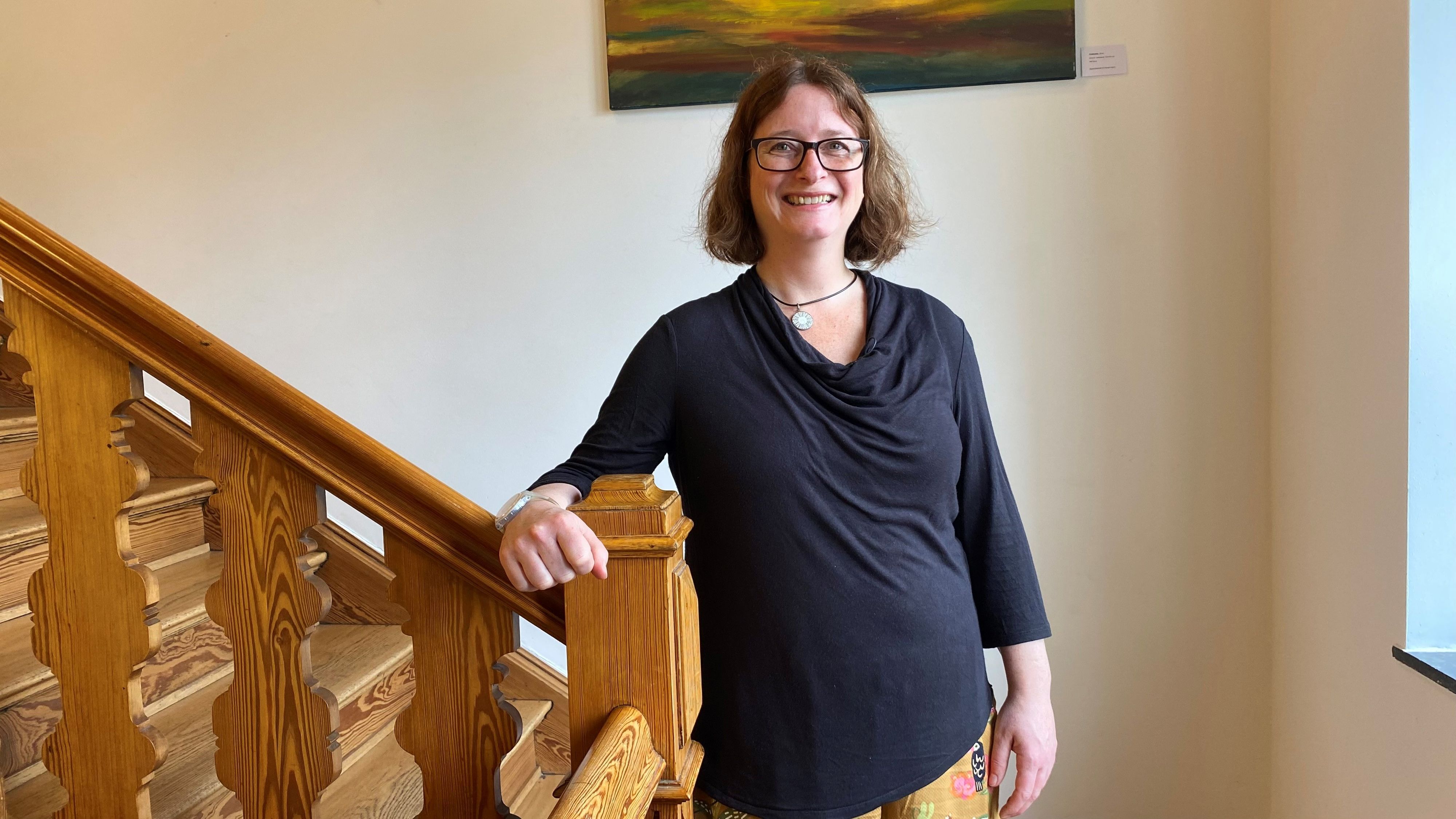 Eine Frau steht an einer hölzernen Treppe.