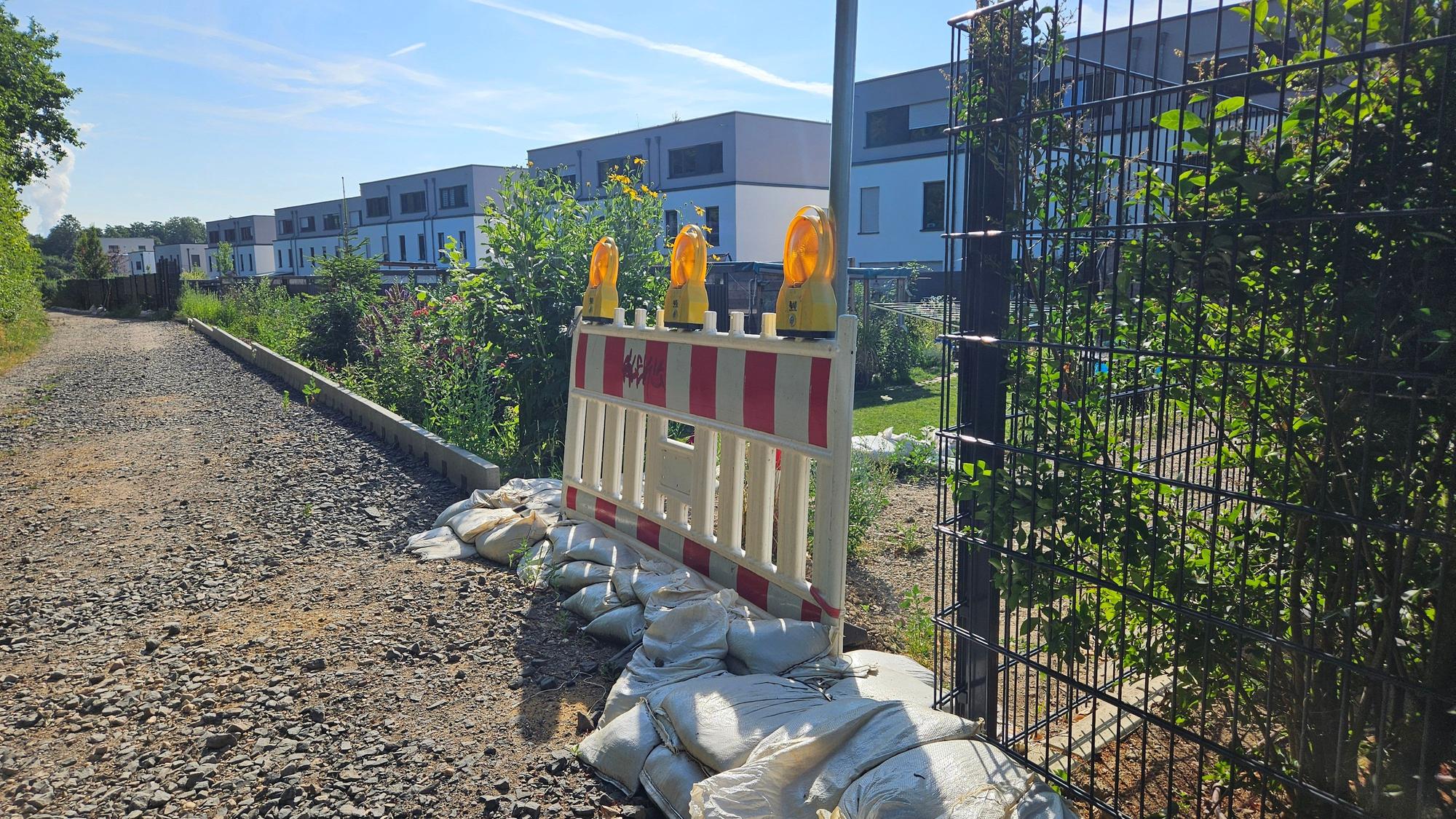 Zu sehen sind Sandsäcke entlang einer Neubausiedlung.