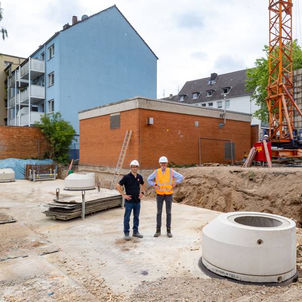 Zwei Männer mit Bauhelmen stehen auf einem großen Betondeckel, es ist das neue Regenrückhaltebecken.