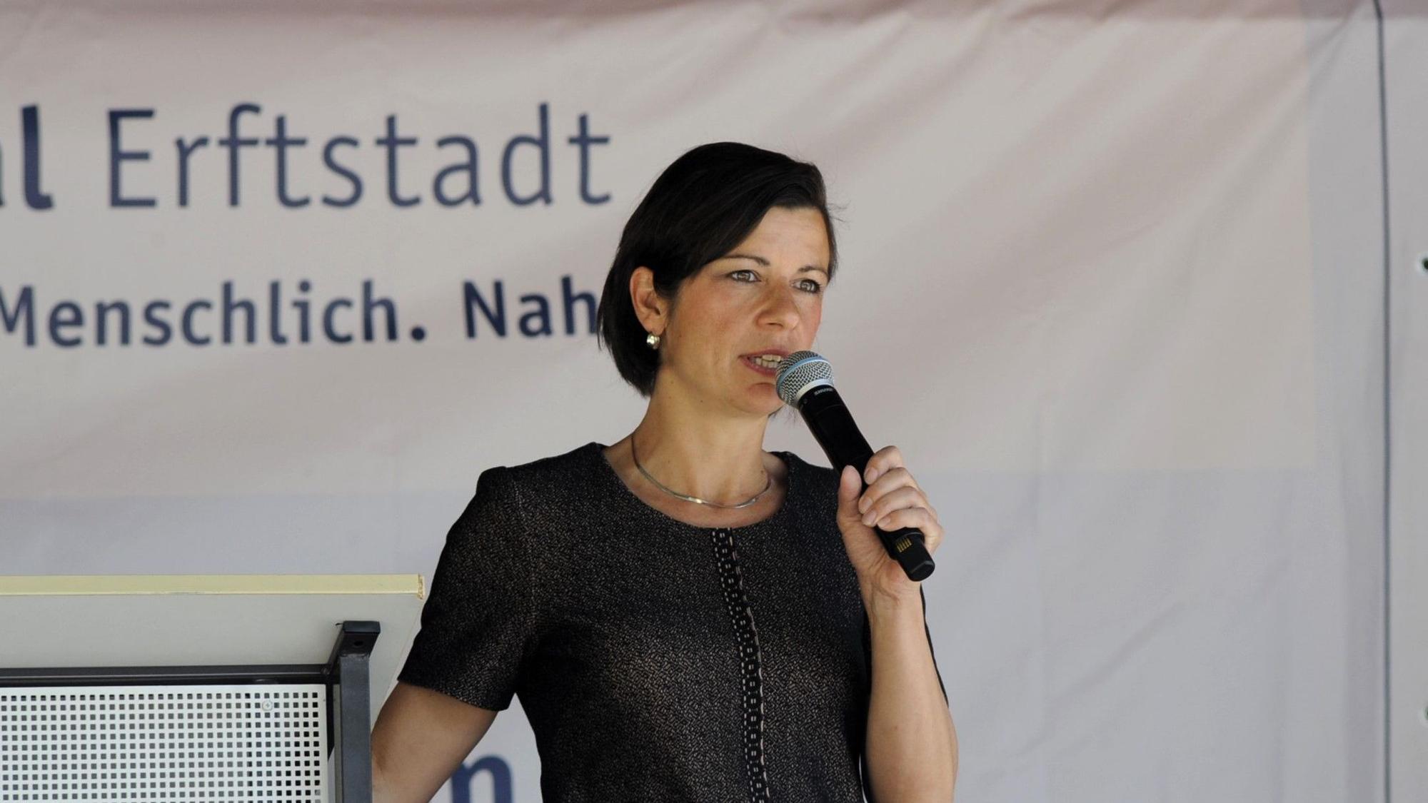 Eine Frau spricht auf einer Bühne in ein Mikrofon.