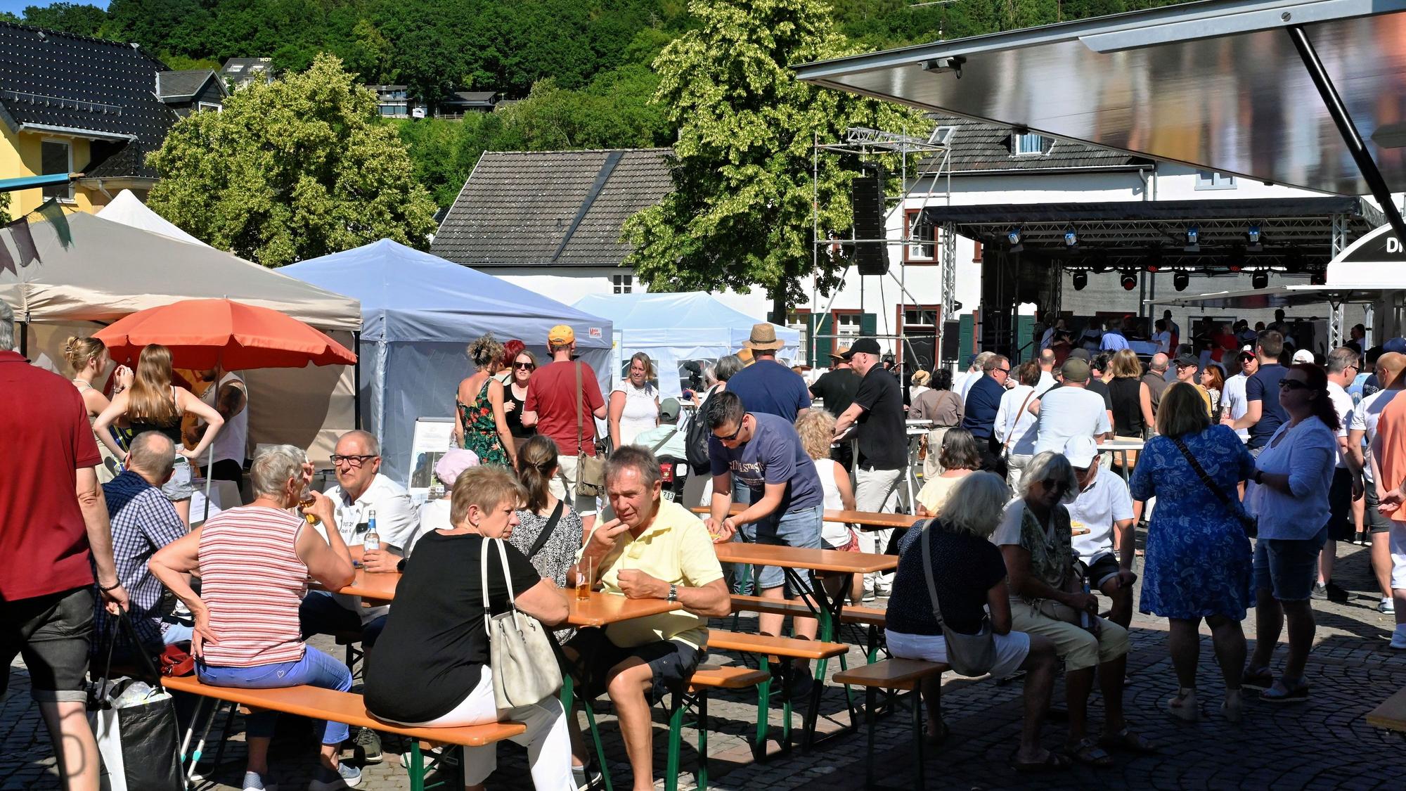 Beim Helferfest zum fünften Jahrestag der Flut in Bad Münstereifel sitzen Besucherinnen und Besucher vor der Bühne an Biertischen zusammen.