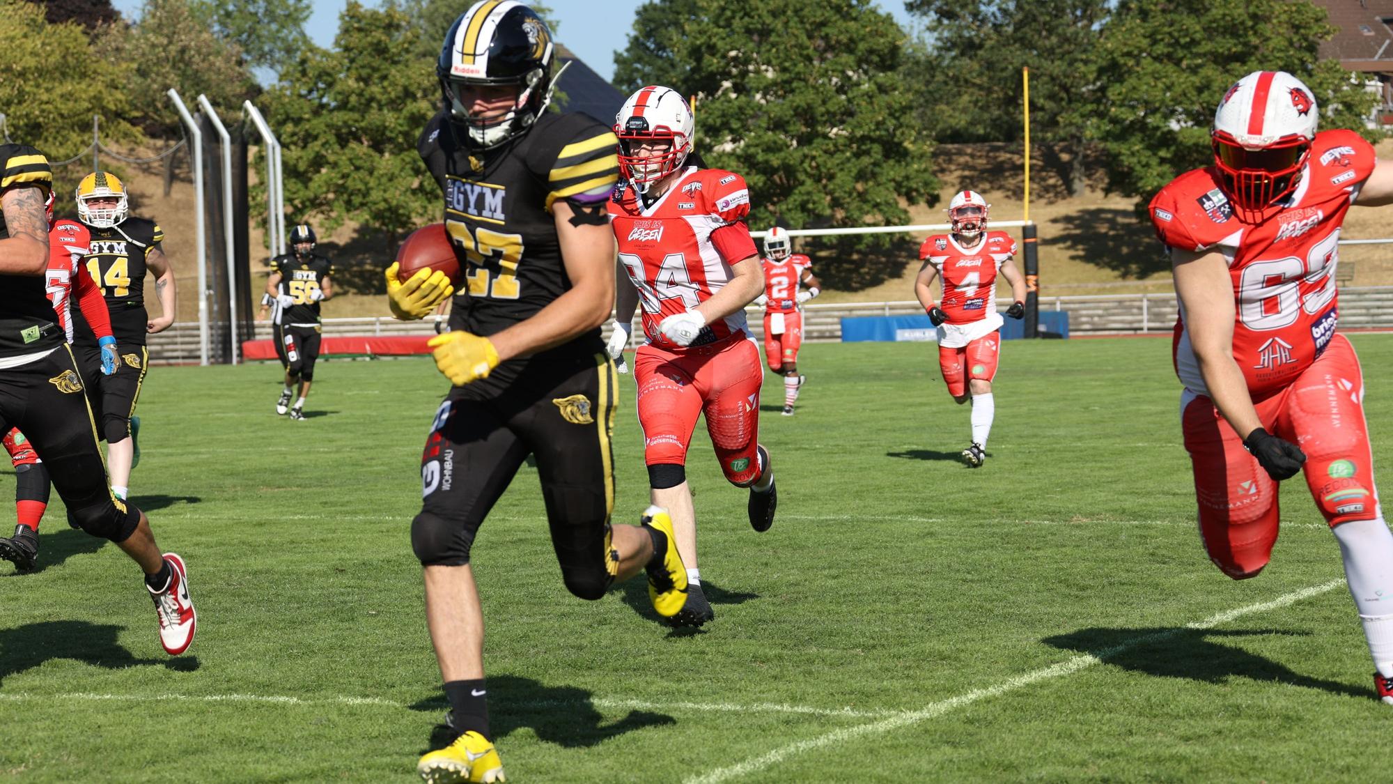 Fynn Handschke läuft, mit dem Football unter dem Arm, den Gegenspielern davon.