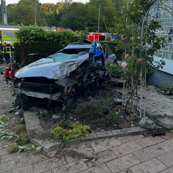 Ein kaputtes Auto in einem Vorgarten.
