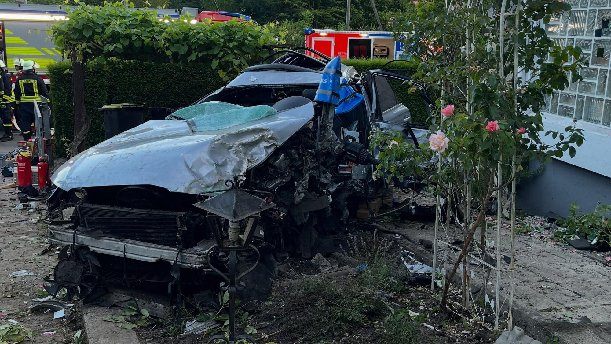 Ein kaputtes Auto in einem Vorgarten.
