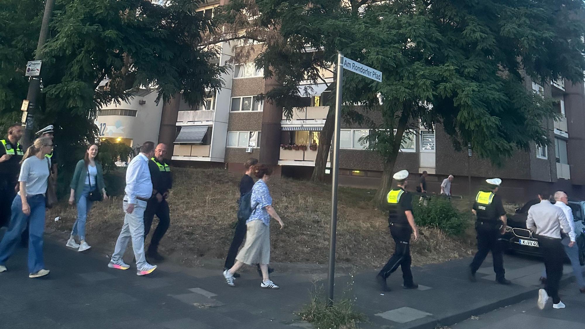 Menschen gehen vor Hochhäusern in Meschenich