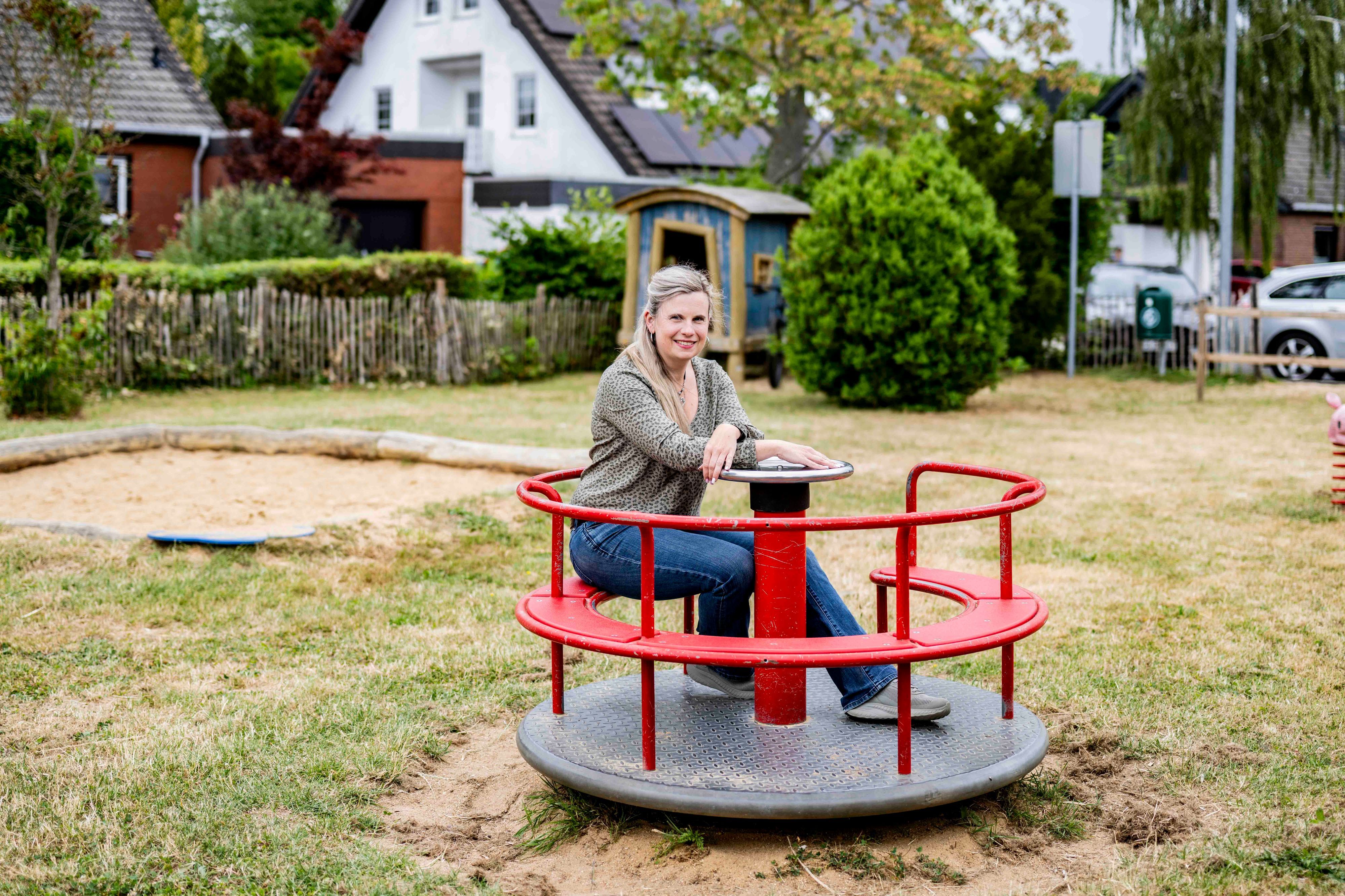 Das Bild zeigt Doro Franz auf einem roten Kinderkarussell.