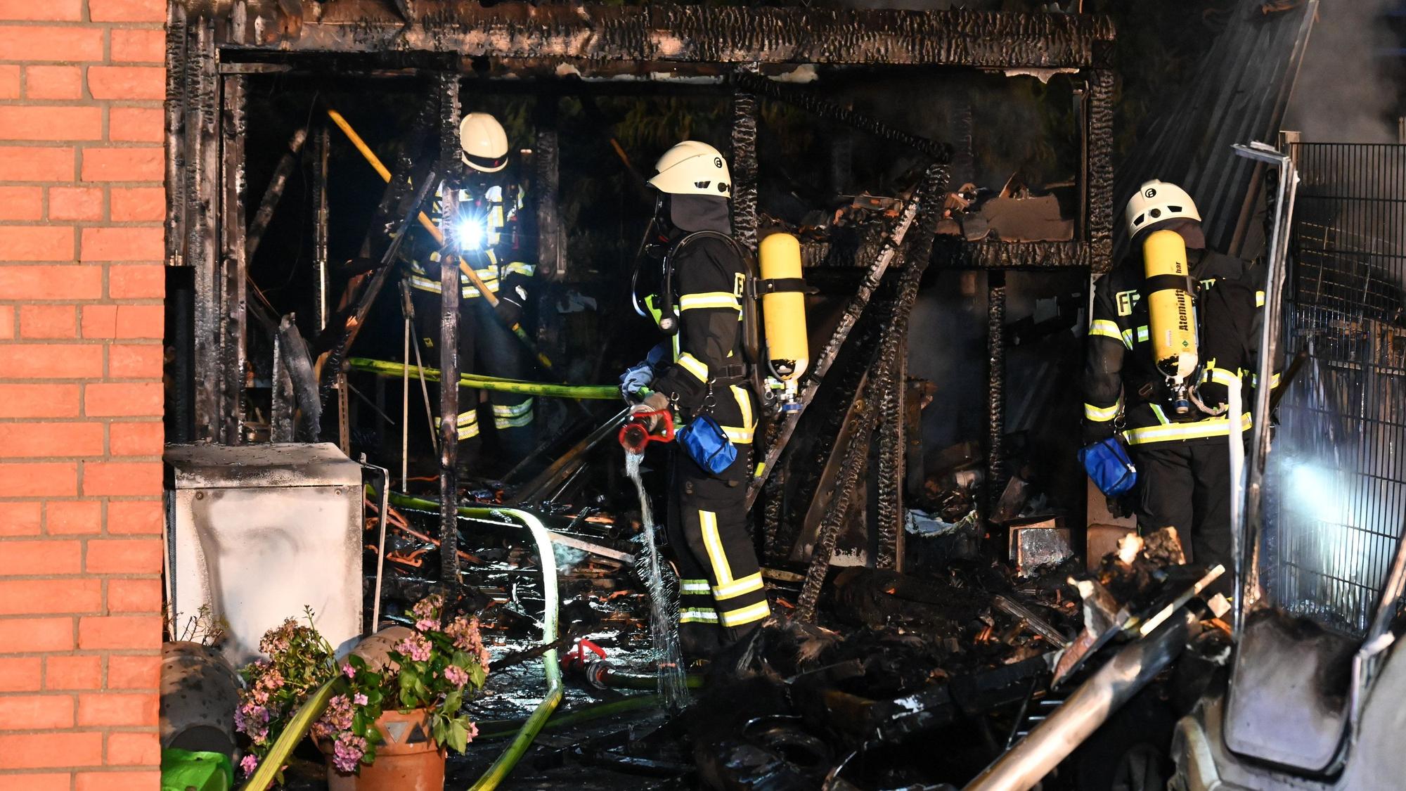 Feuerwehrleute löschen einen Schuppen. Alles ist verkohlt.