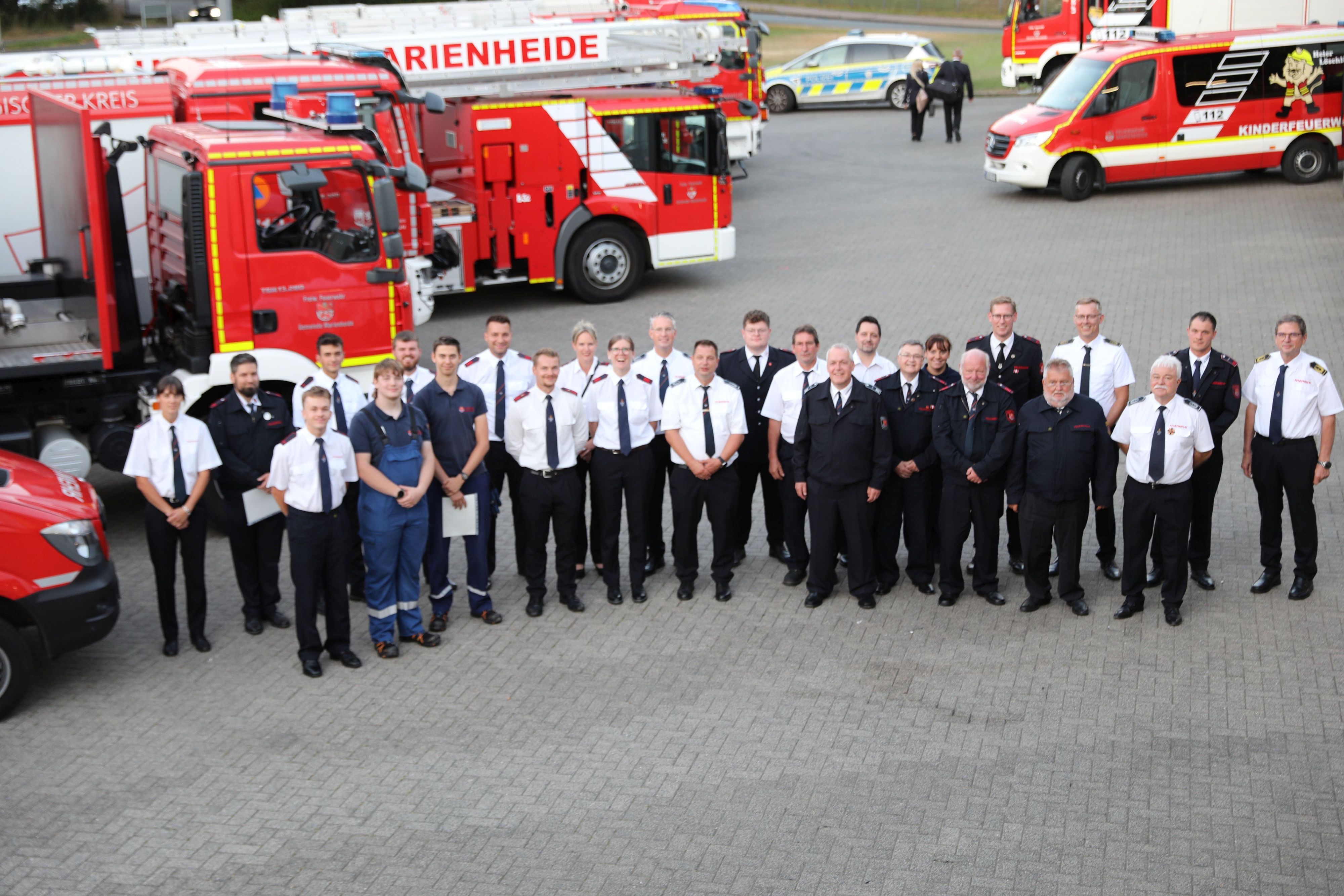 Ein Gruppenbild vor Feuerwehrfahrzeugen.