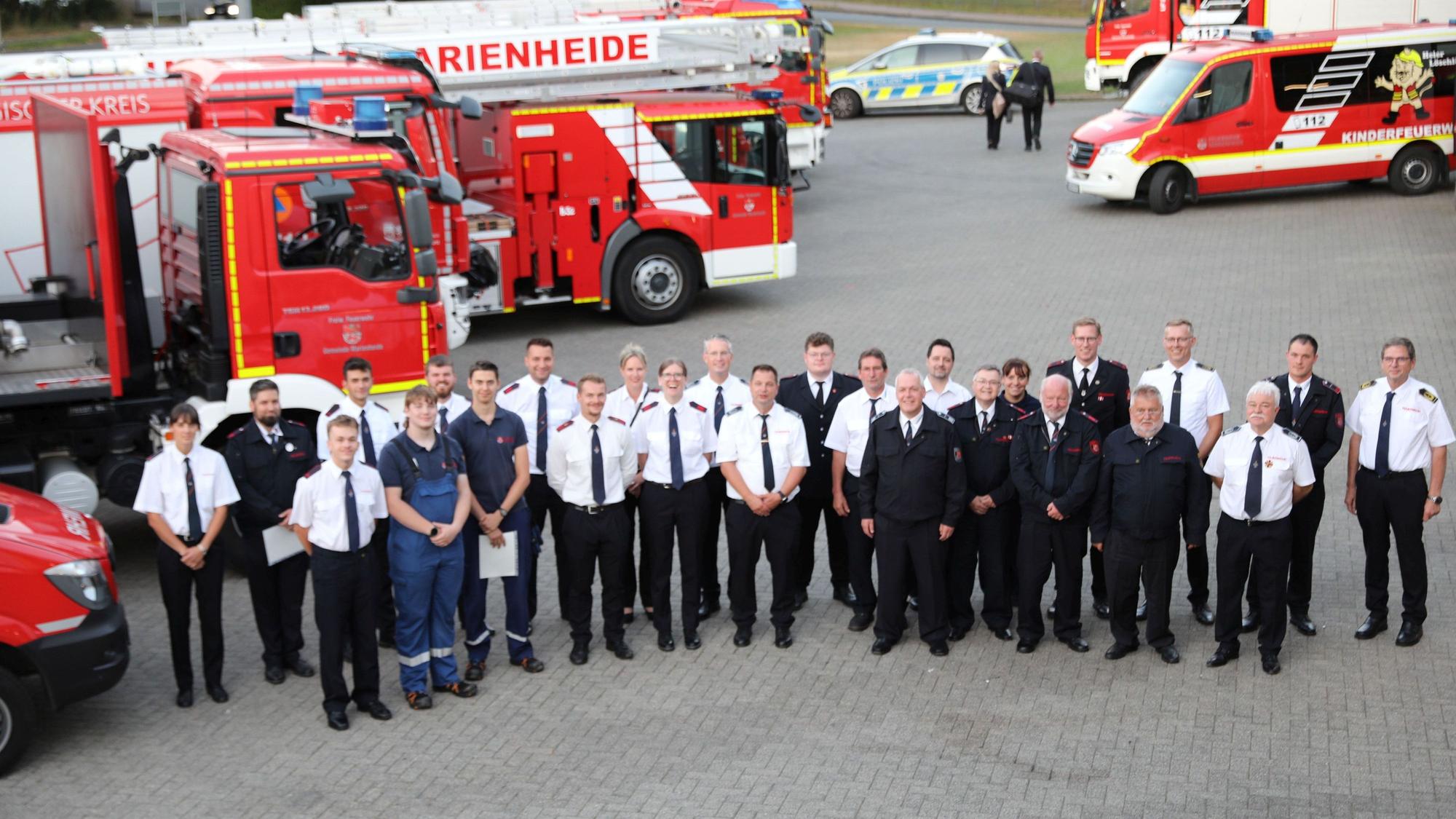 Ein Gruppenbild vor Feuerwehrfahrzeugen.