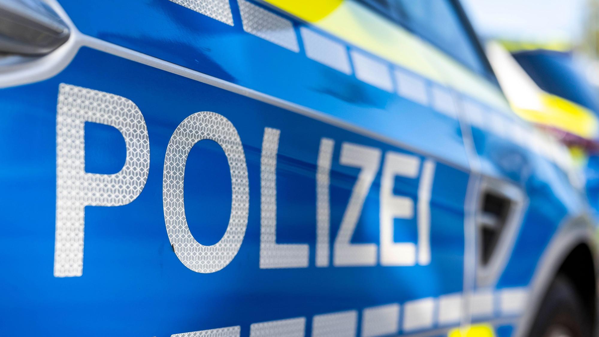 An der Tür eines Streifenwagens steht der Schriftzug „Polizei“.