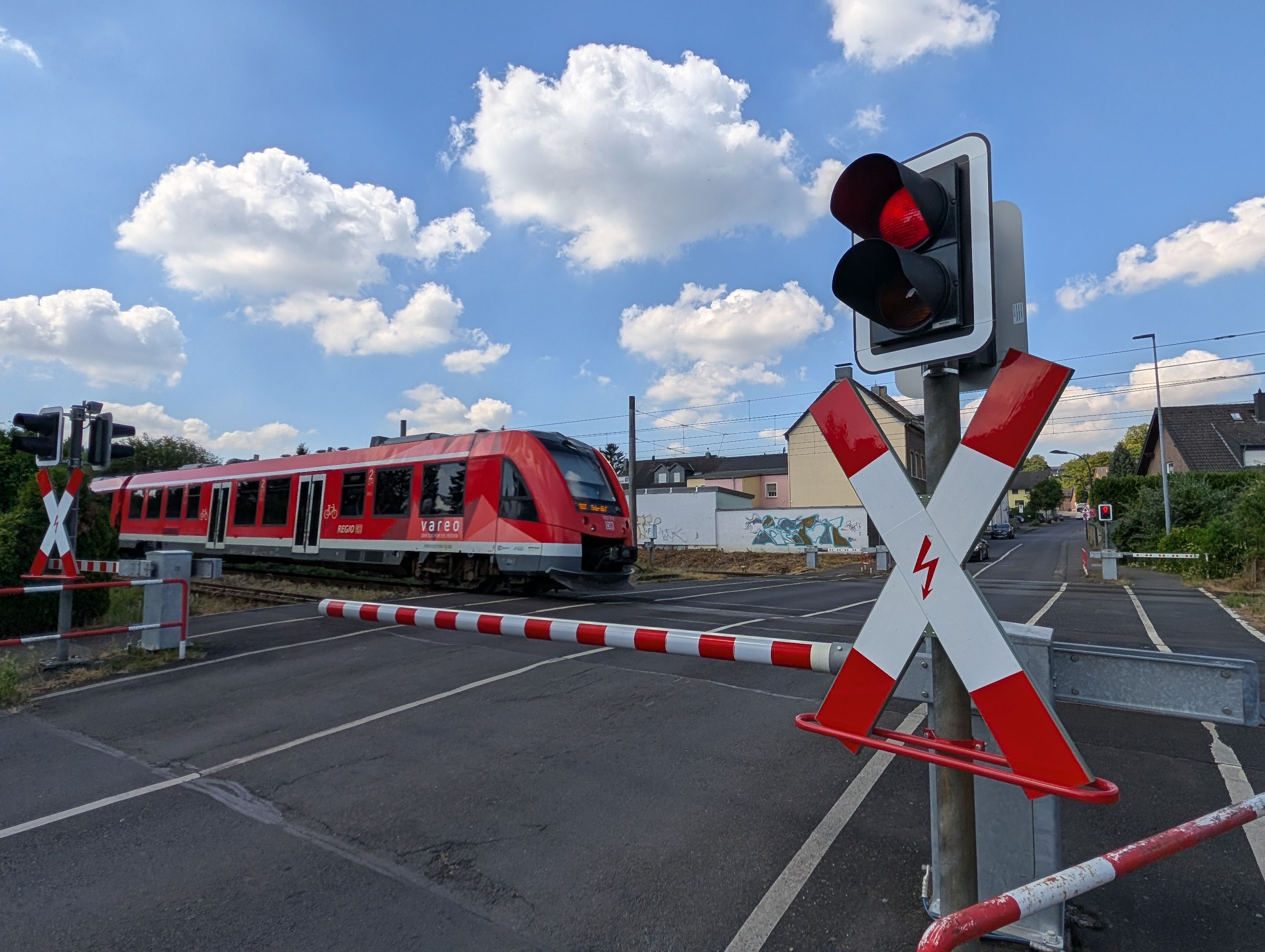 Eine Regionalbahn passiert den Bahnübergang an der Schmittenstraße in Hürth-Fischenich.