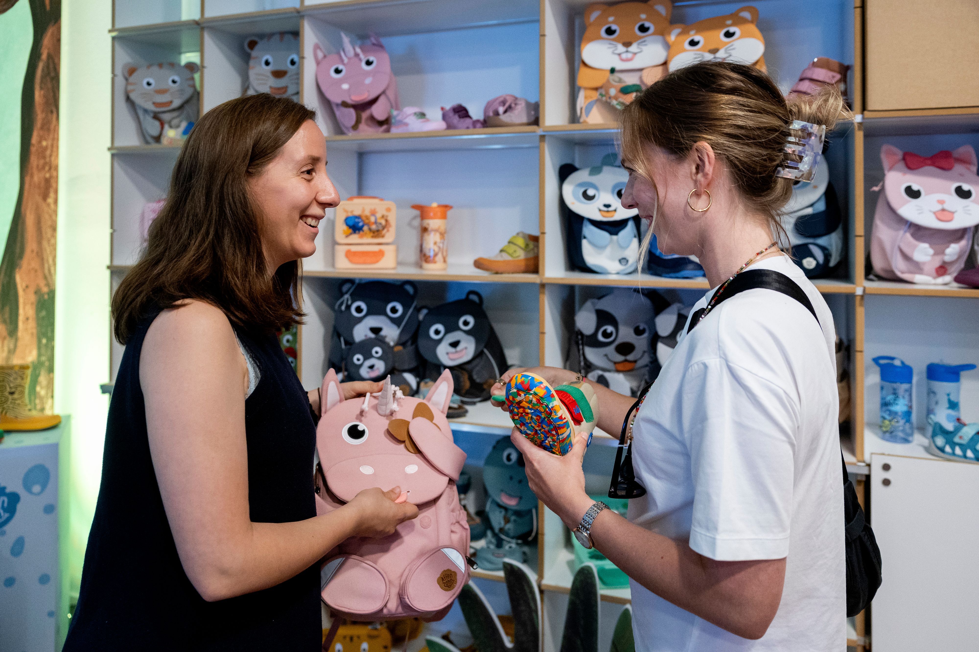 Zwei Frauen unterhalten sich in einem Laden über Fond-of-Produkte, die in ihren Händen und in den Regalen zu sehen sind.