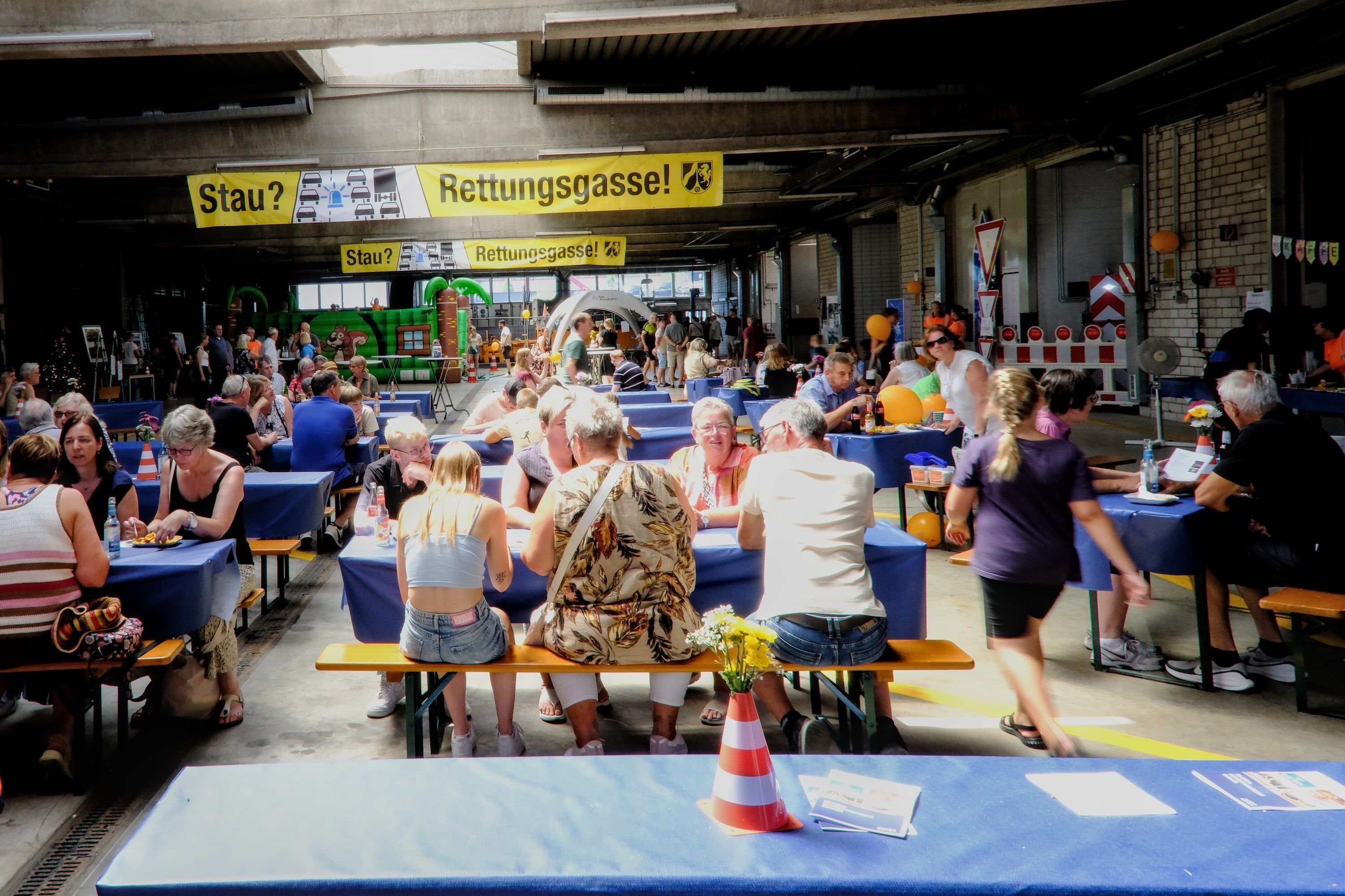 Besucher sitzen an Bierbänken in einem umdekorierten Lagerraum.