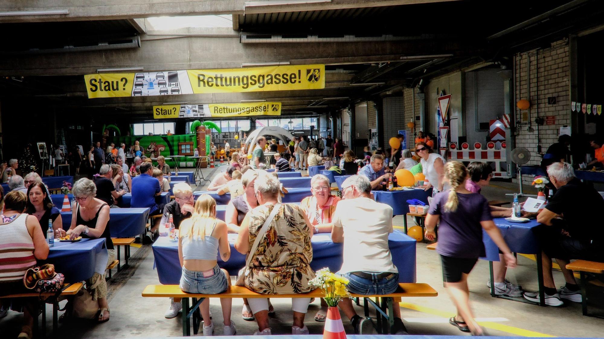 Besucher sitzen an Bierbänken in einem umdekorierten Lagerraum.