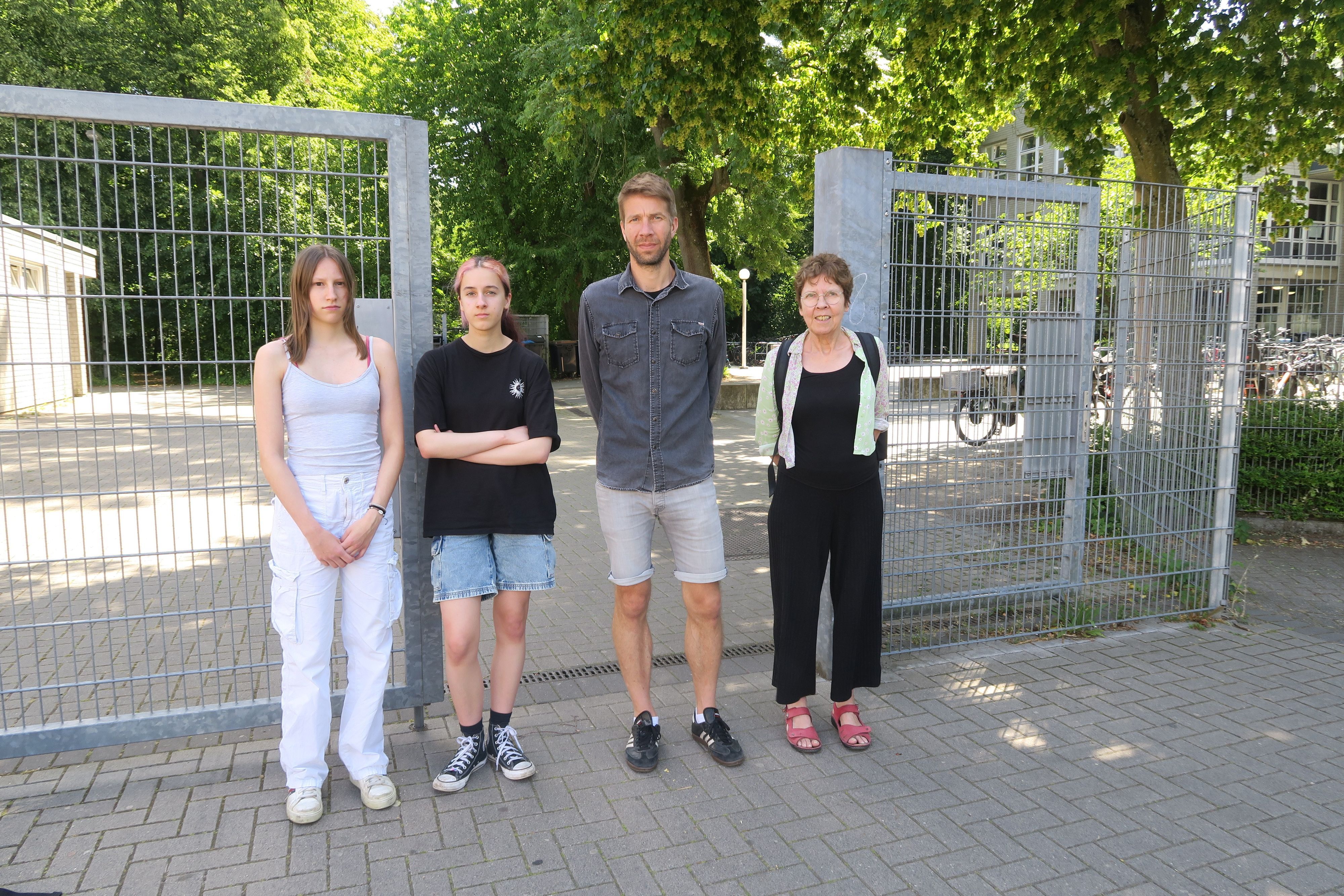 Zwei Schülerinnen, ein Lehrer und eine Lehrerin stehen vor dem offenen Schultor der Gesamtschule in Bocklemünd.