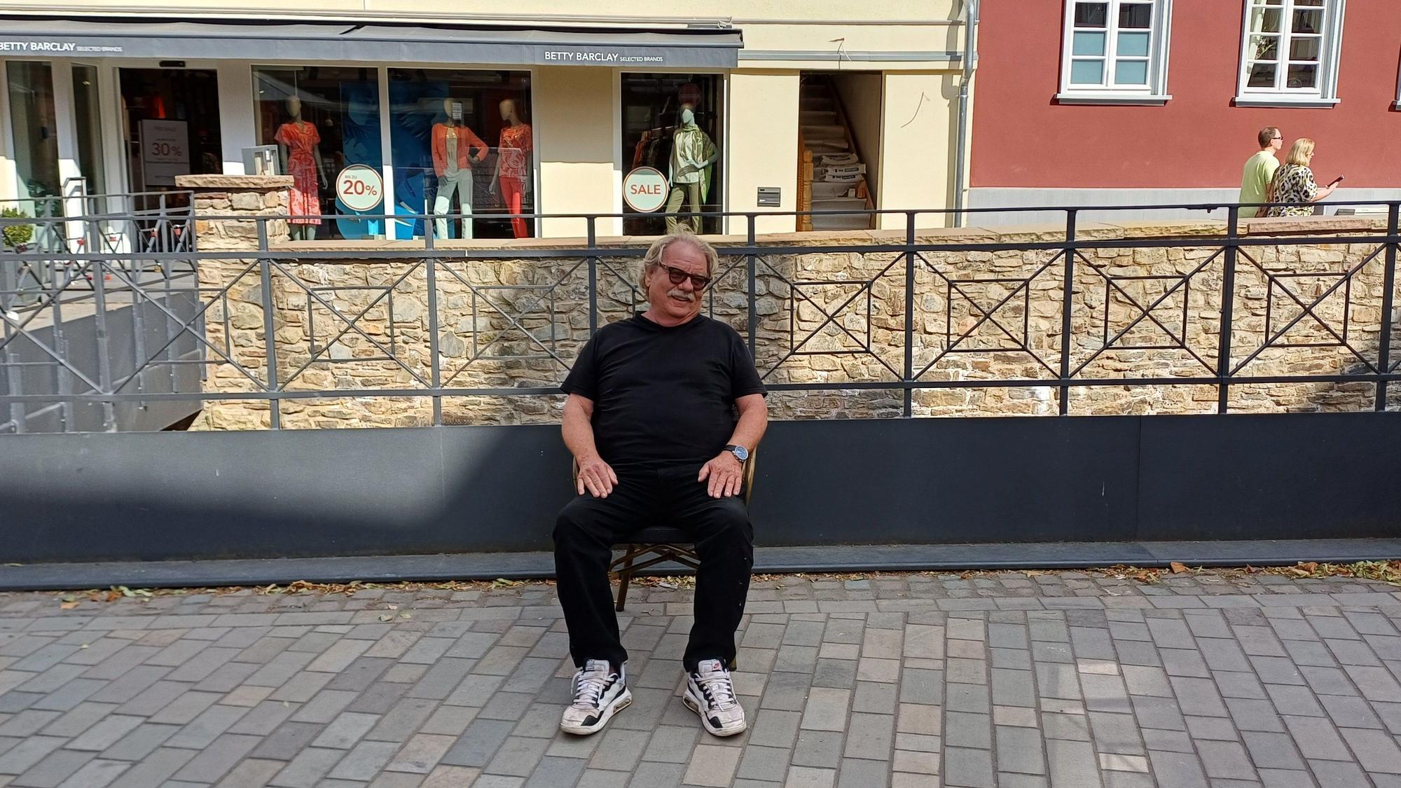 Günter Portz sitzt auf einem Stuhl auf einer bisher vom Printenhaus genutzten Außengastronomiefläche.