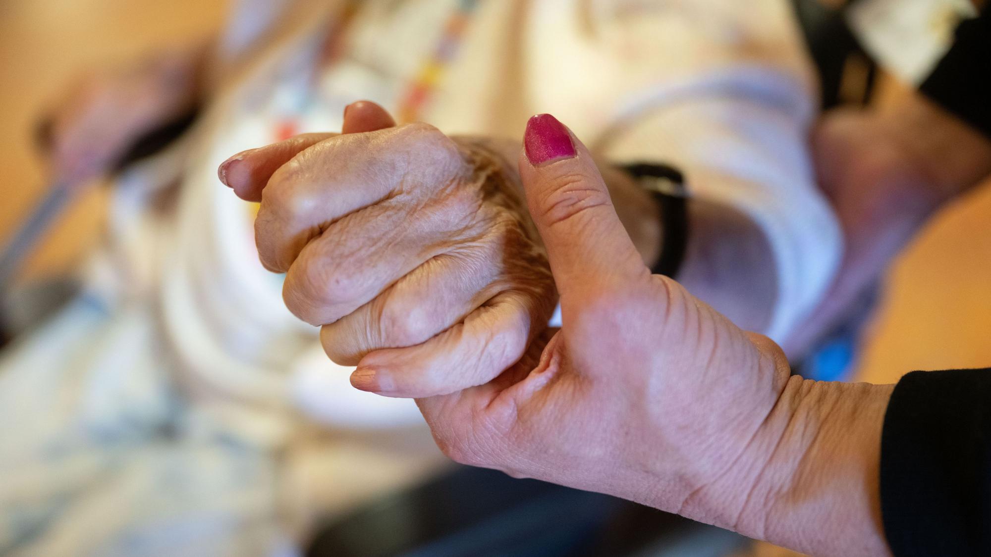 Eine Physiotherapeutin hält die Hand und den Ellenbogen einer Pflegebedürftigen. (Symbolbild)