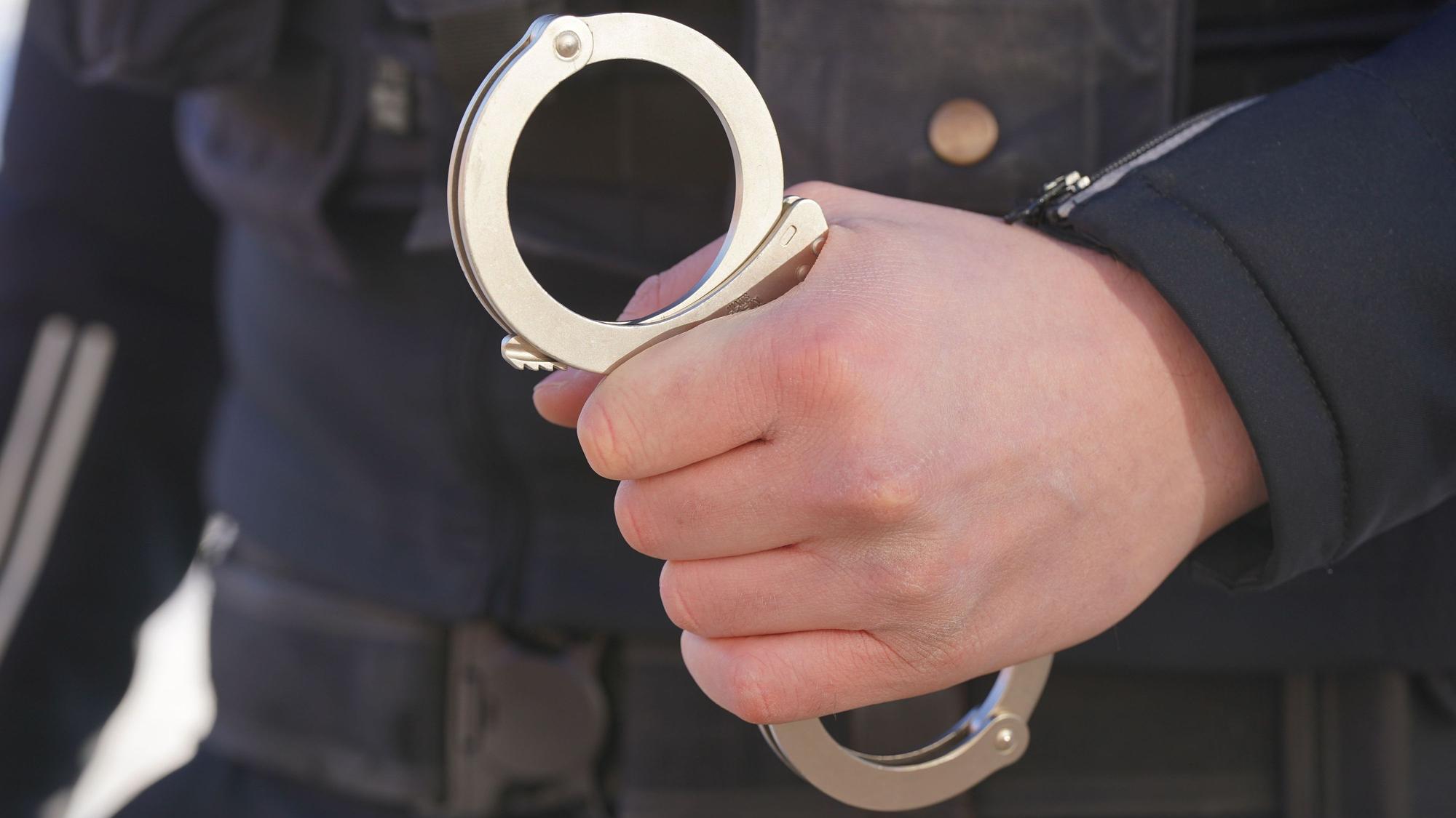 Ein Polizist hält Handschellen in der Hand. (Symbolbild)