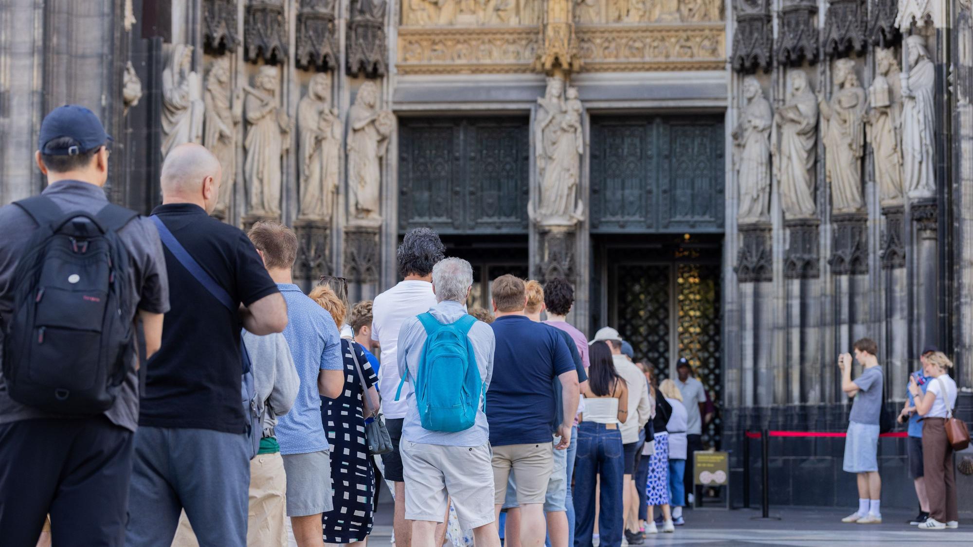 Vor dem Haupteingang des Kölner Doms hat sich eine lange Schlange gebildet.
