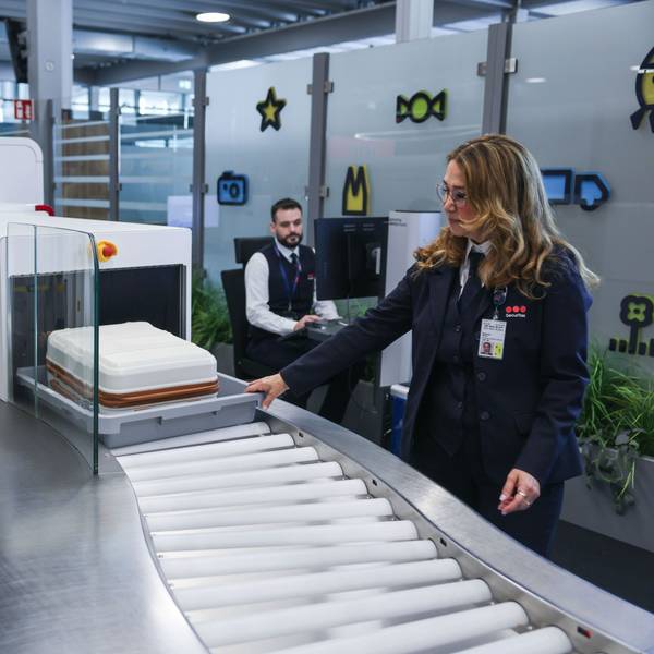 Die Mitarbeiterin einer Sicherheitsfirma schiebt im Sicherheitsbereich am Flughafen Köln/Bonn einen Koffer in einen Scanner. Eine neue Anlage mit elf modernen CT-Kontrollspuren und Scannern soll künftig für schnellere, komfortablere und effizientere Abläufe sorgen.