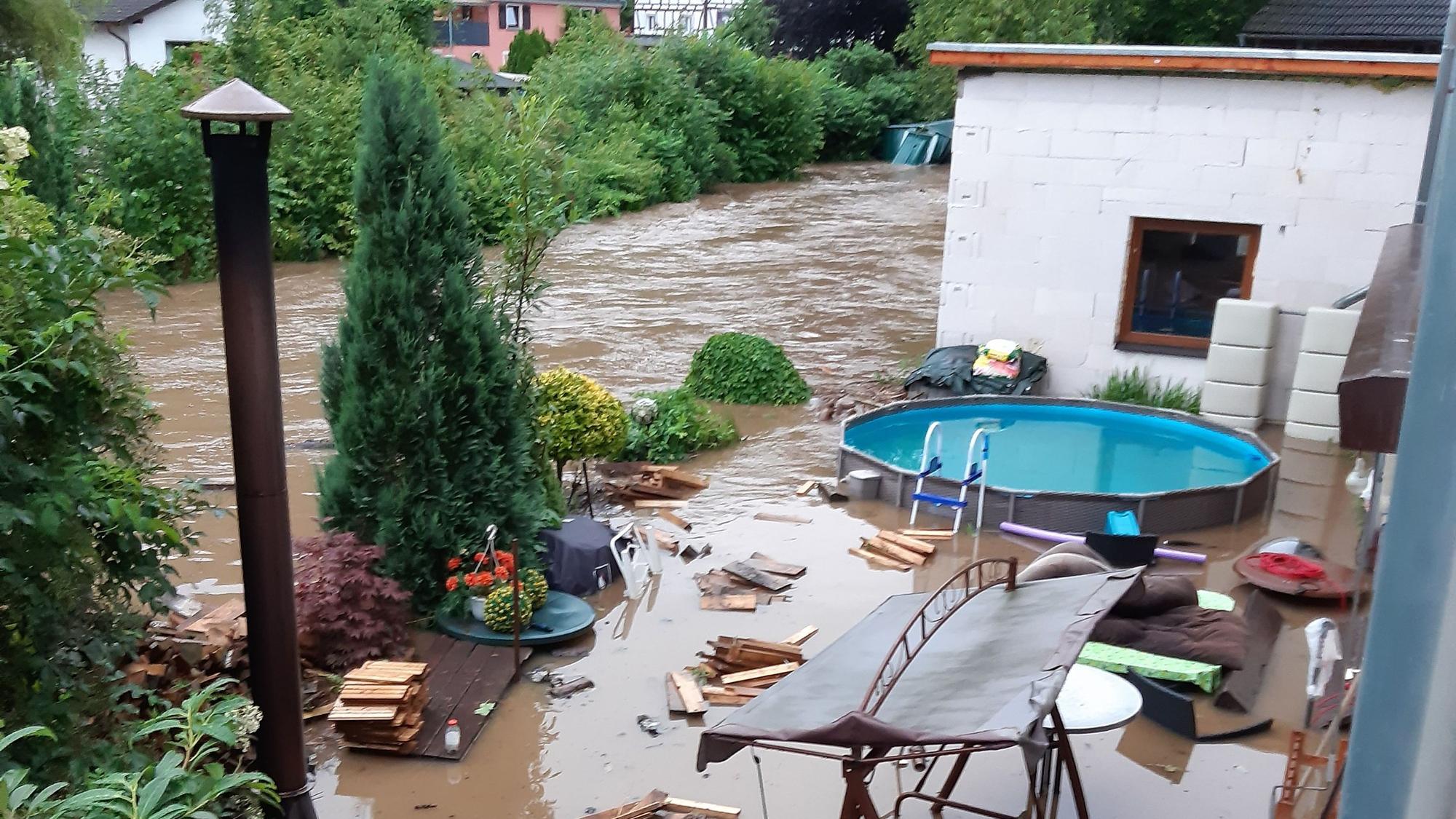 Ein überfluteteter Garten am Flussufer.