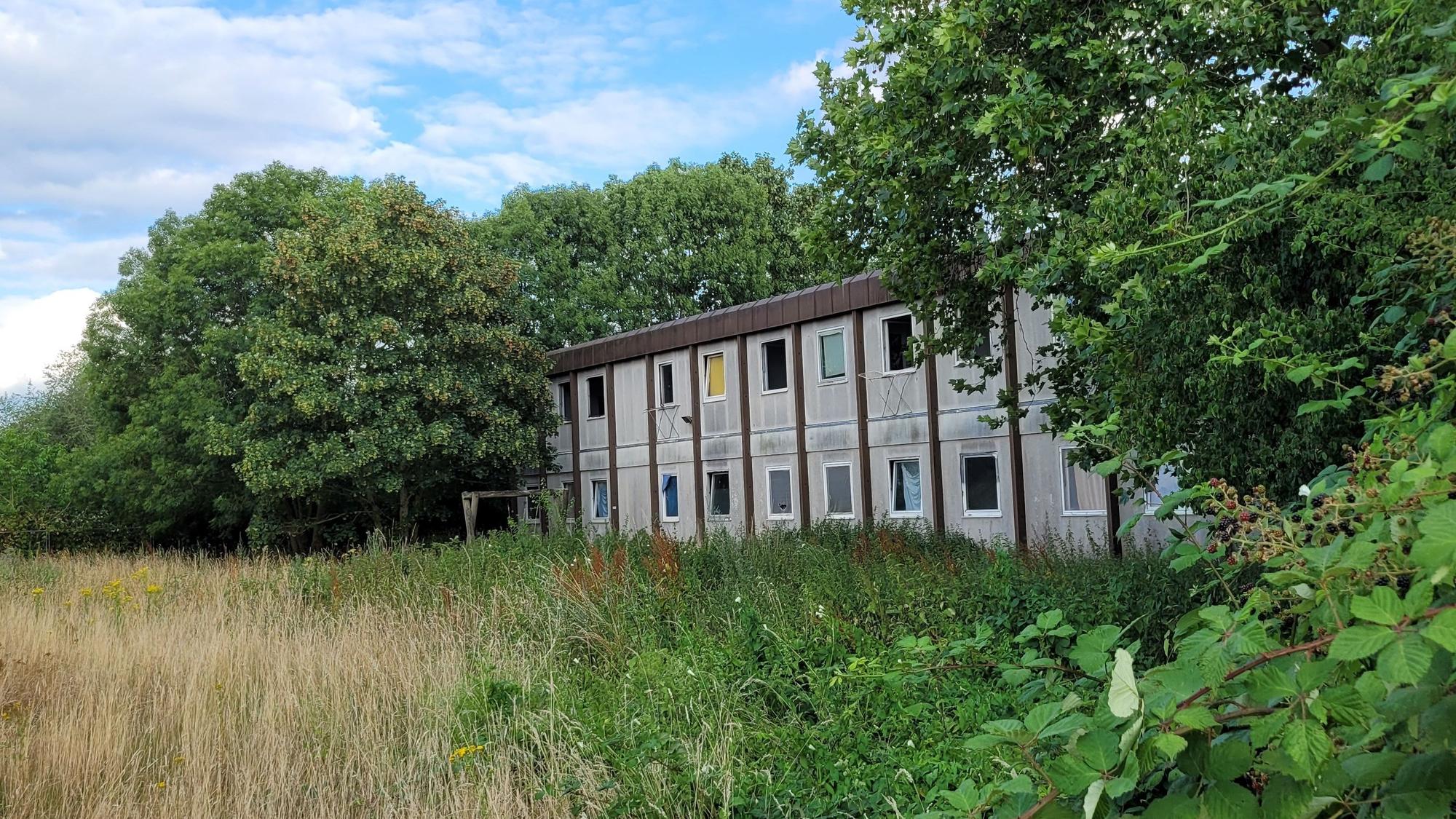 Ein Gebäude mit grauer Fassade, es wirkt heruntergekommen.