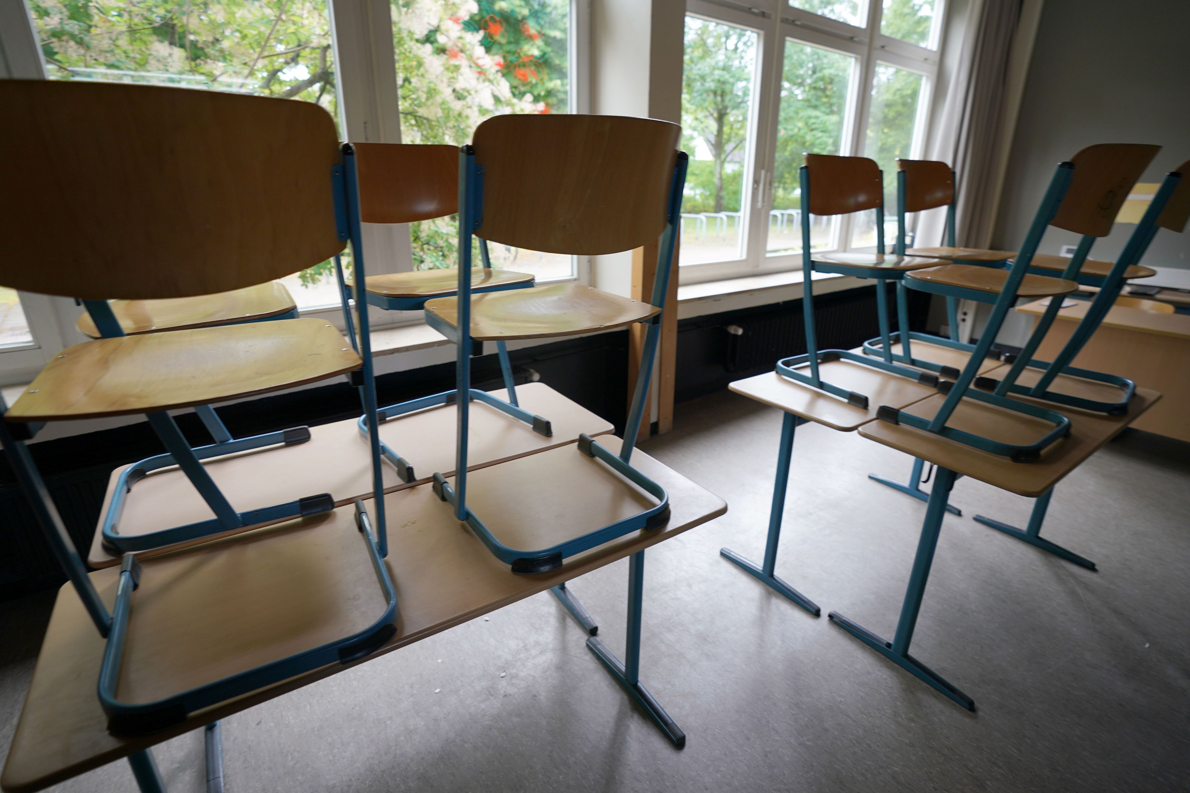 Stühle stehen in einem Klassenraum in einer Schule auf den Tischen.
