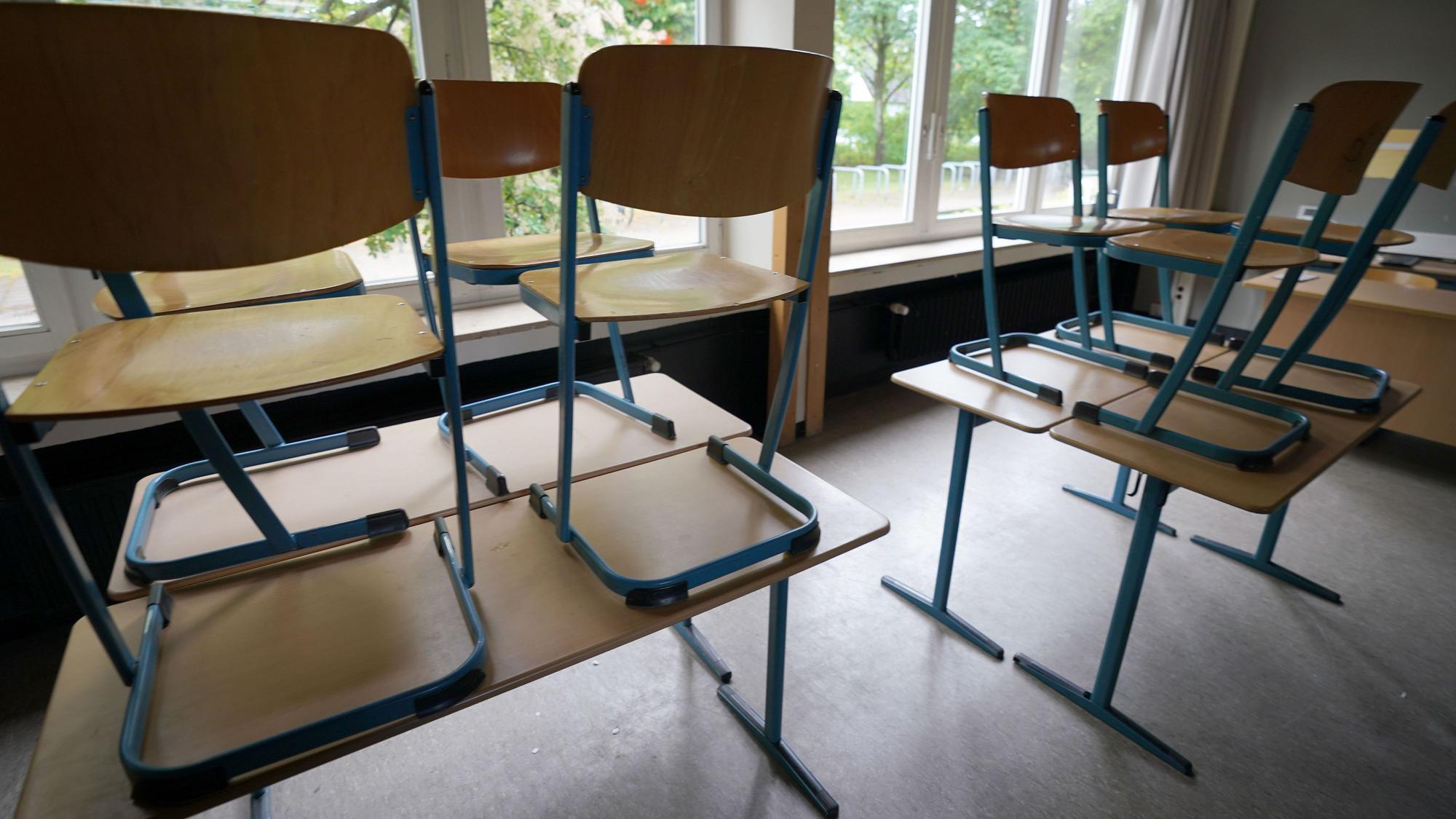 Stühle stehen in einem Klassenraum in einer Schule auf den Tischen.