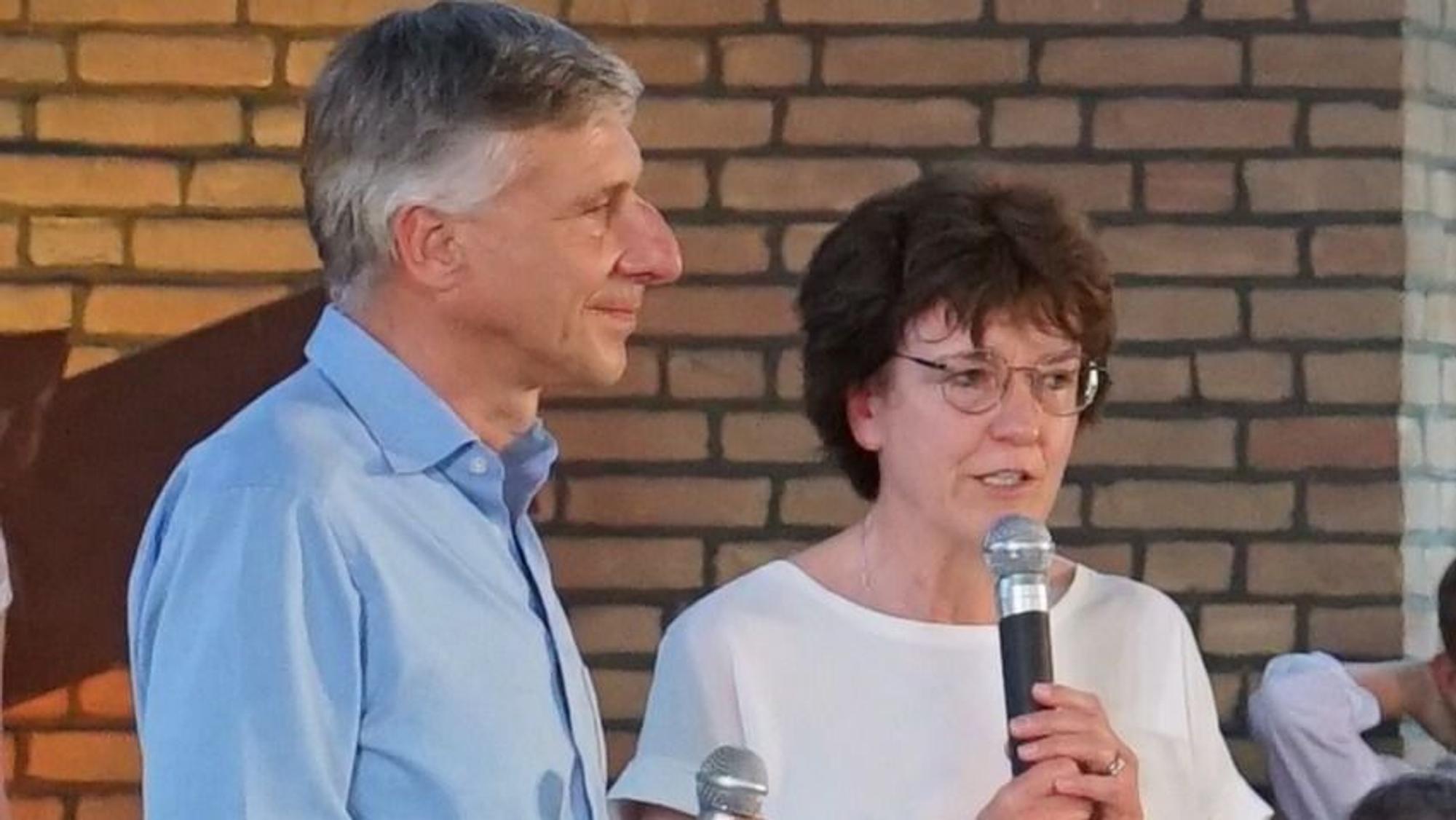 Ein Mann und eine Frau stehen nebeneinander und sprechen in ein Mikrofon.
