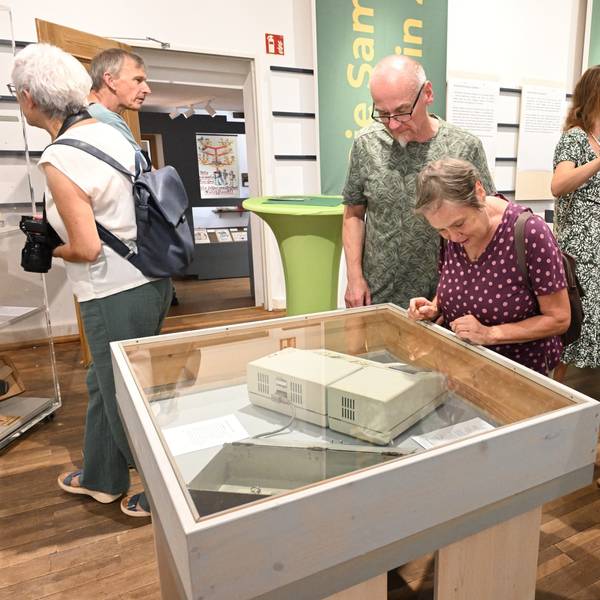 Gäste laufen durchs Museum und betrachten Objekte.