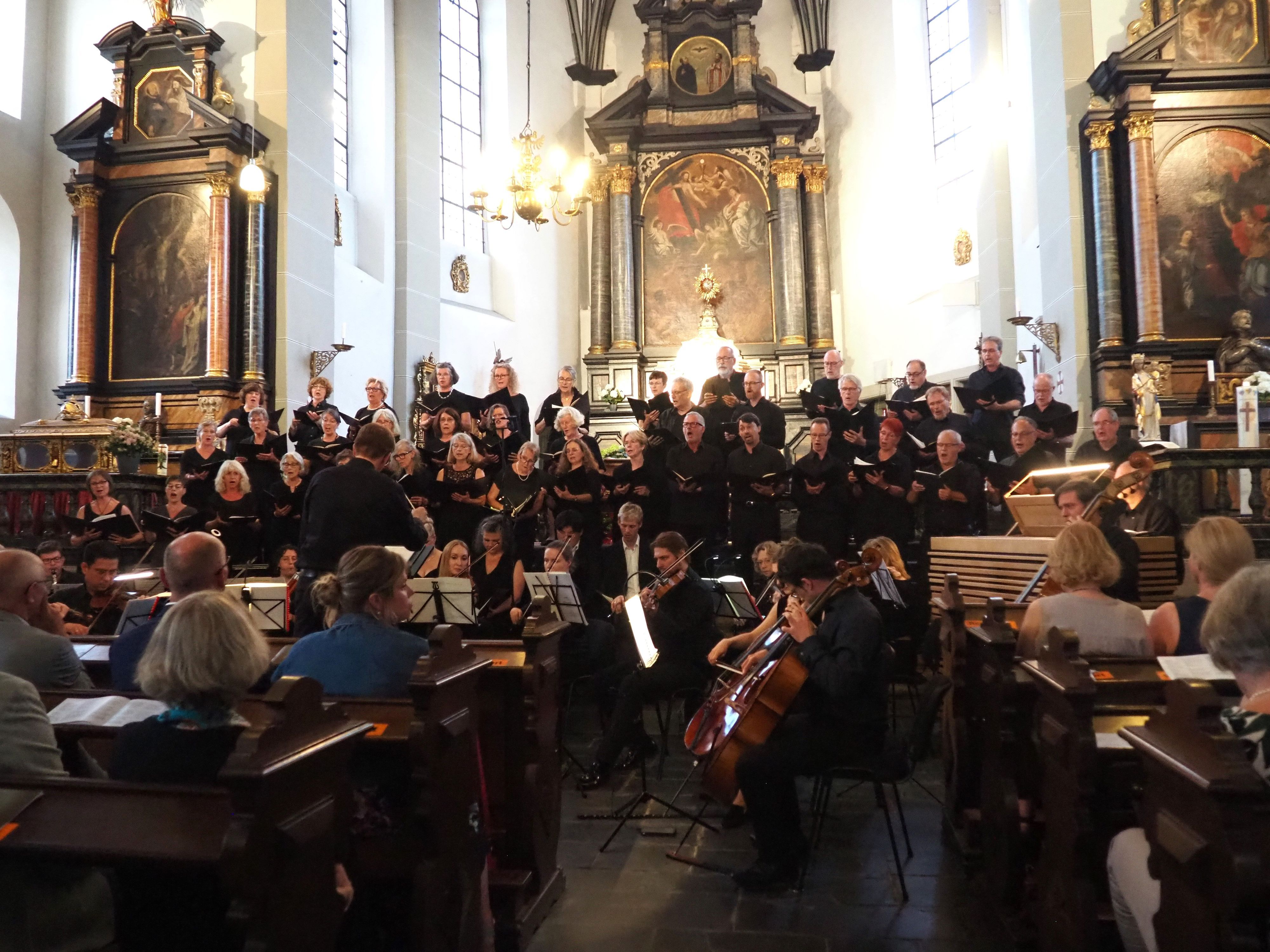 Im Vordergrund sitzen die Orchestermusiker, dahinter stehen die Chormitglieder.