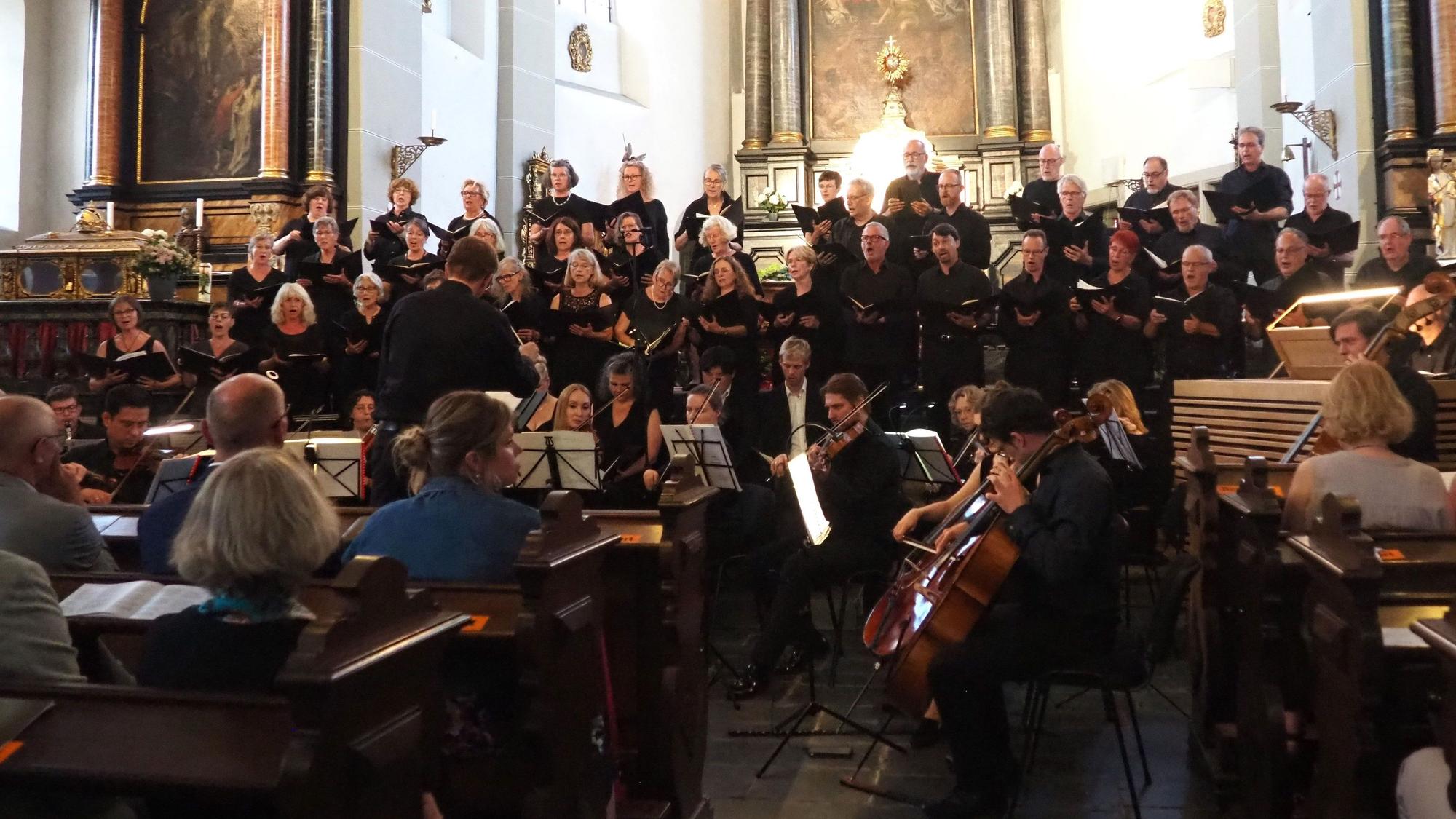 Im Vordergrund sitzen die Orchestermusiker, dahinter stehen die Chormitglieder.
