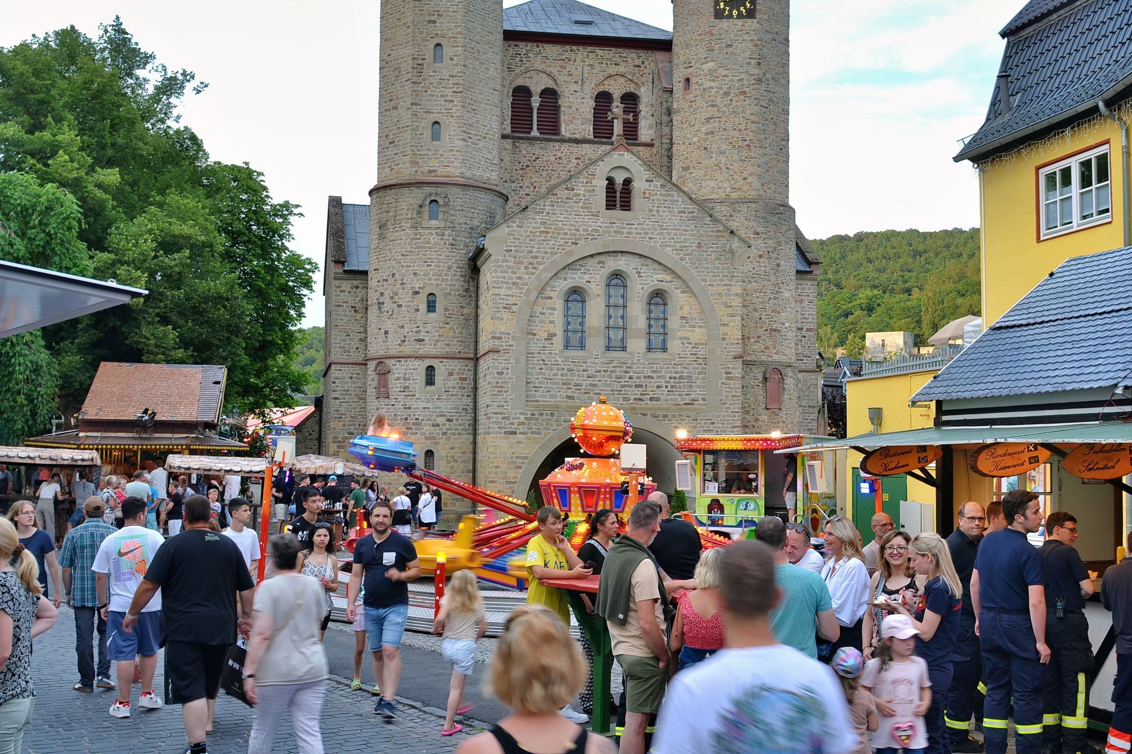 Ein Bild von der Kirmes im Sommer 2024. Menschen gehen über die Langenhecke, im Hintergrund ist die Stiftskirche zu sehen.