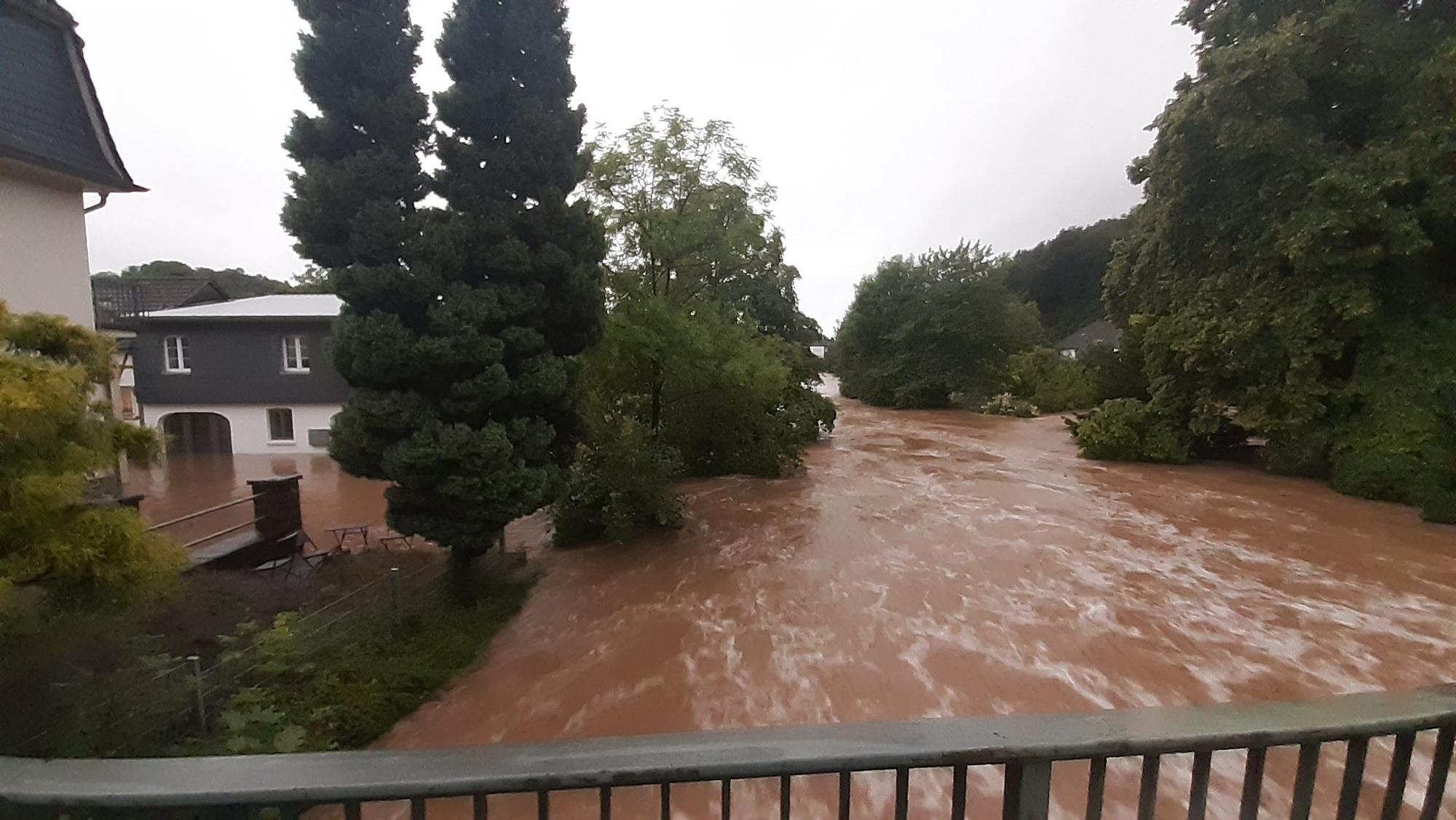 Zu sehen ist ein über die Ufer getretener, reißender Fluss in schlammigem Braum.