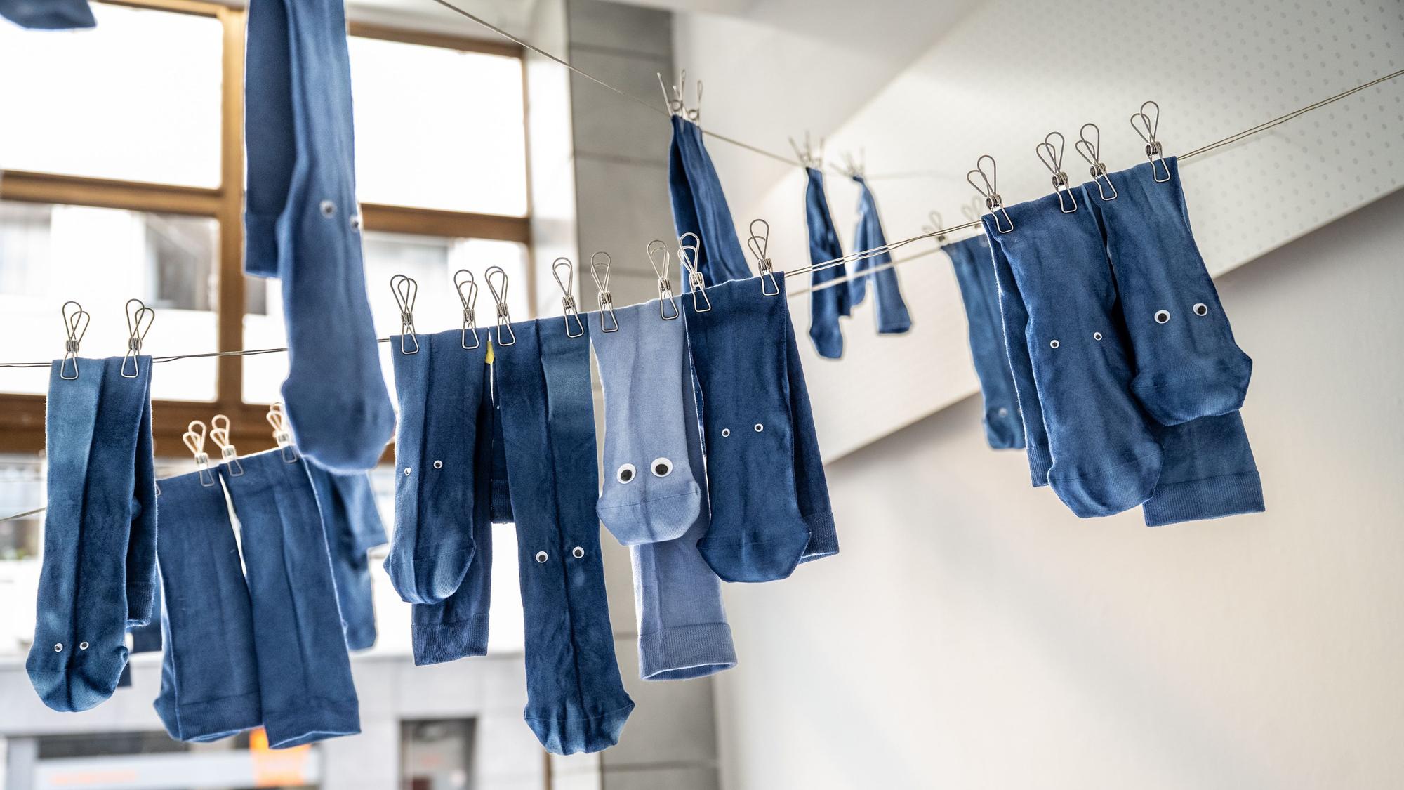 Blaue Socken mit Kulleraugen hängen an einer Leine