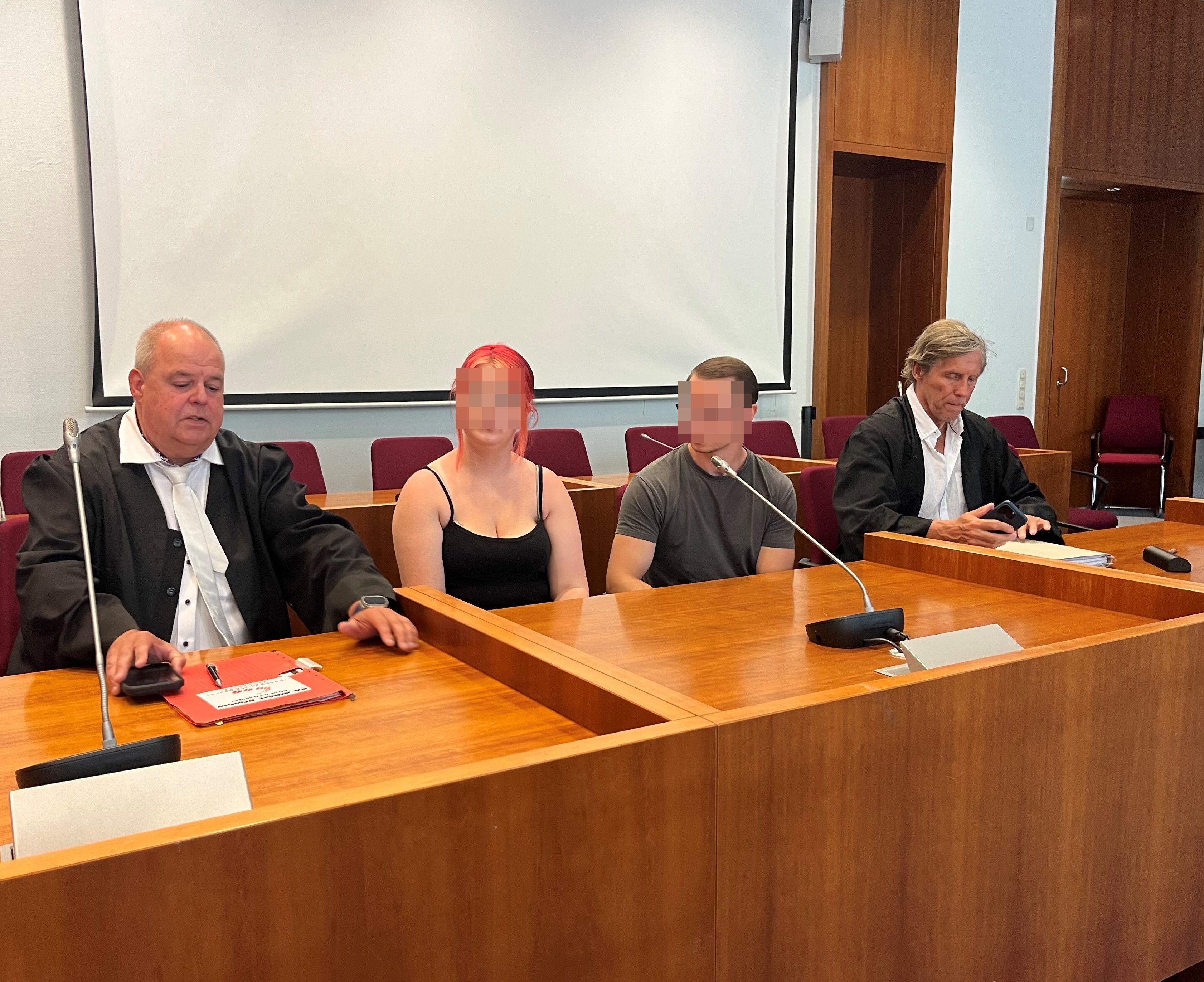 Das Bild zeigt die Angeklagten und ihre Anwälte im Gerichtssaal.