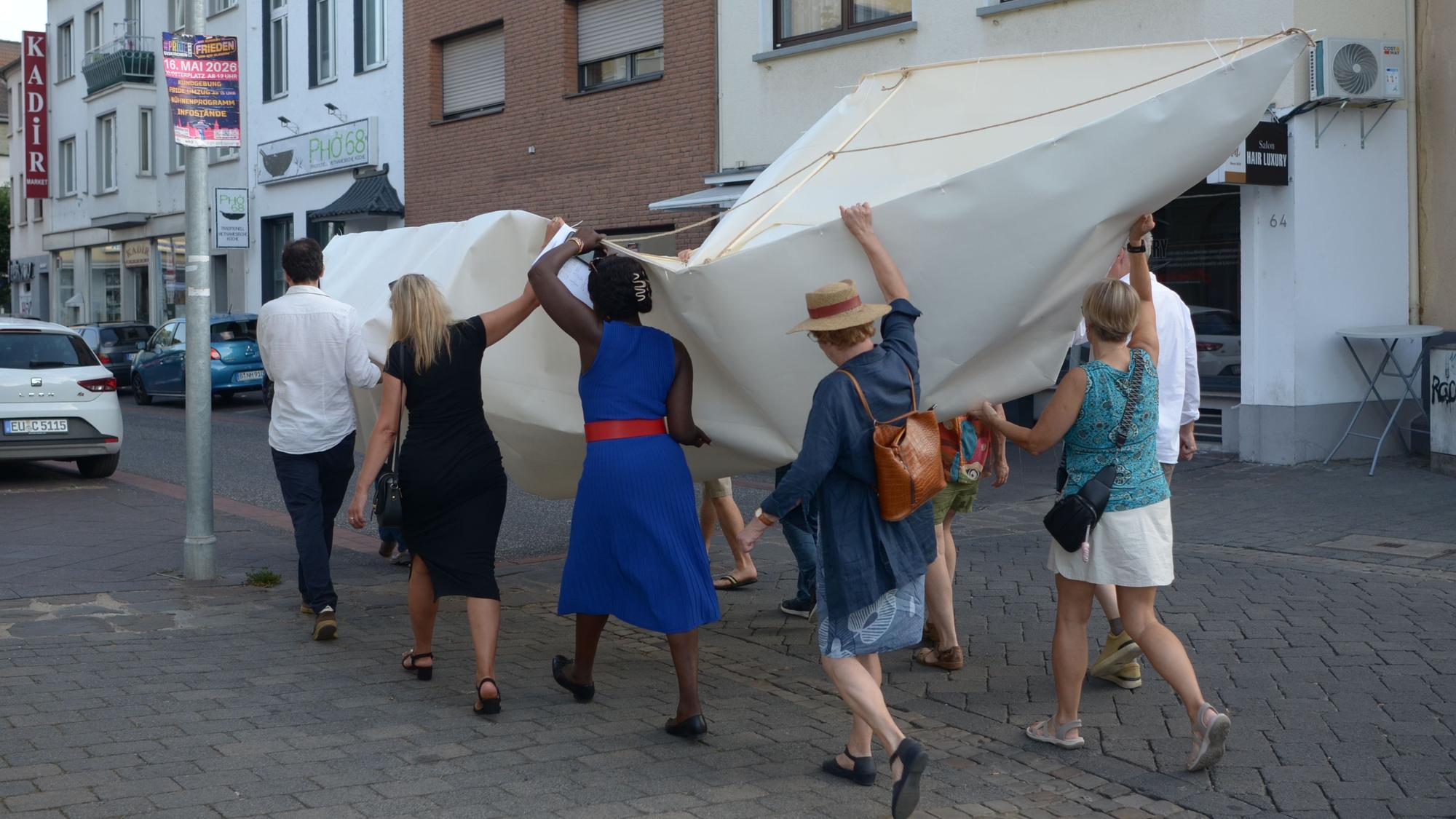 Die Frauen und Männer tragen das Boot durch eine Straße.