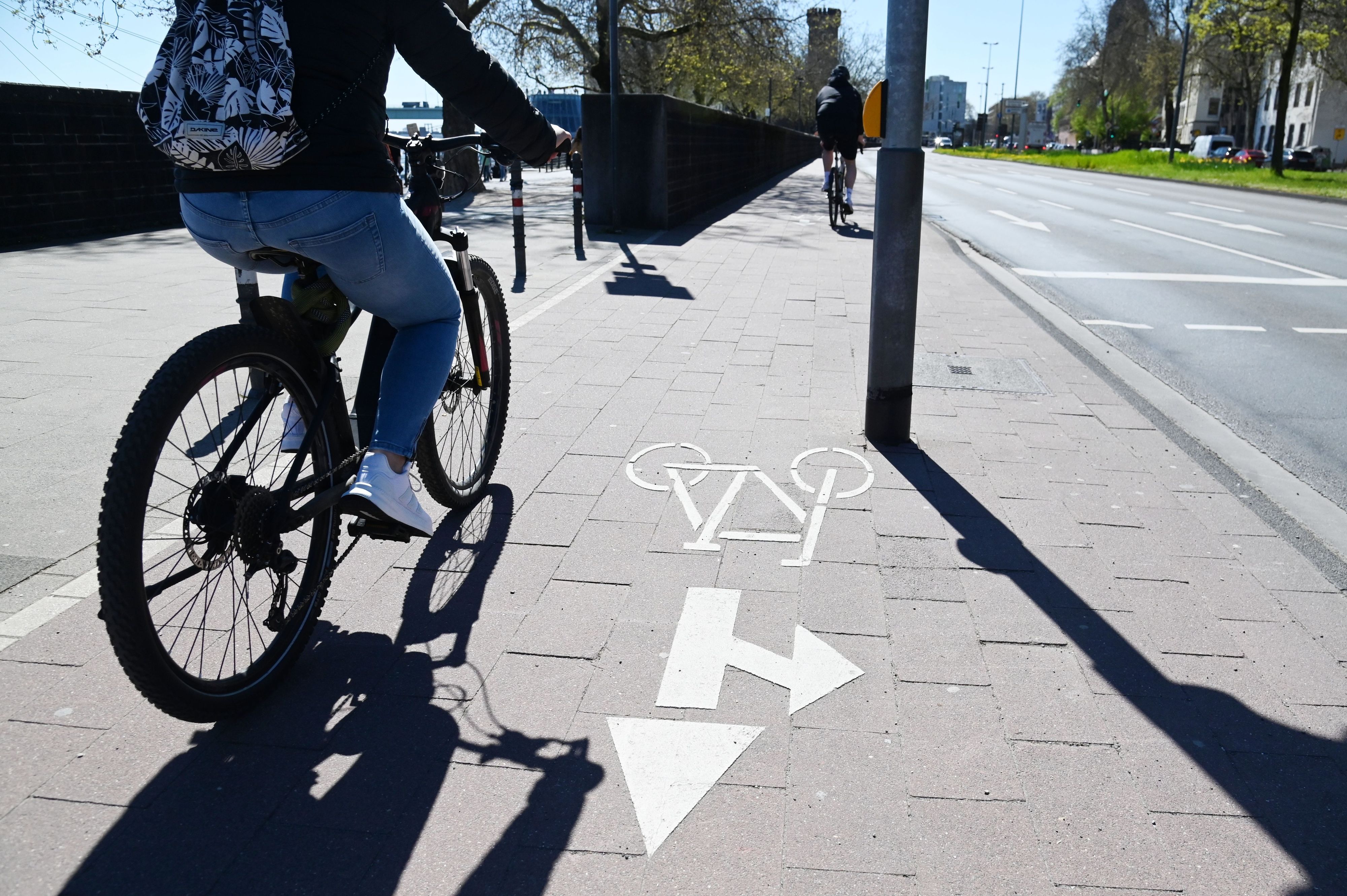 Ein Radfahrer fährt am Rheinufer in der Kölner Altstadt entlang. (Archivbild)