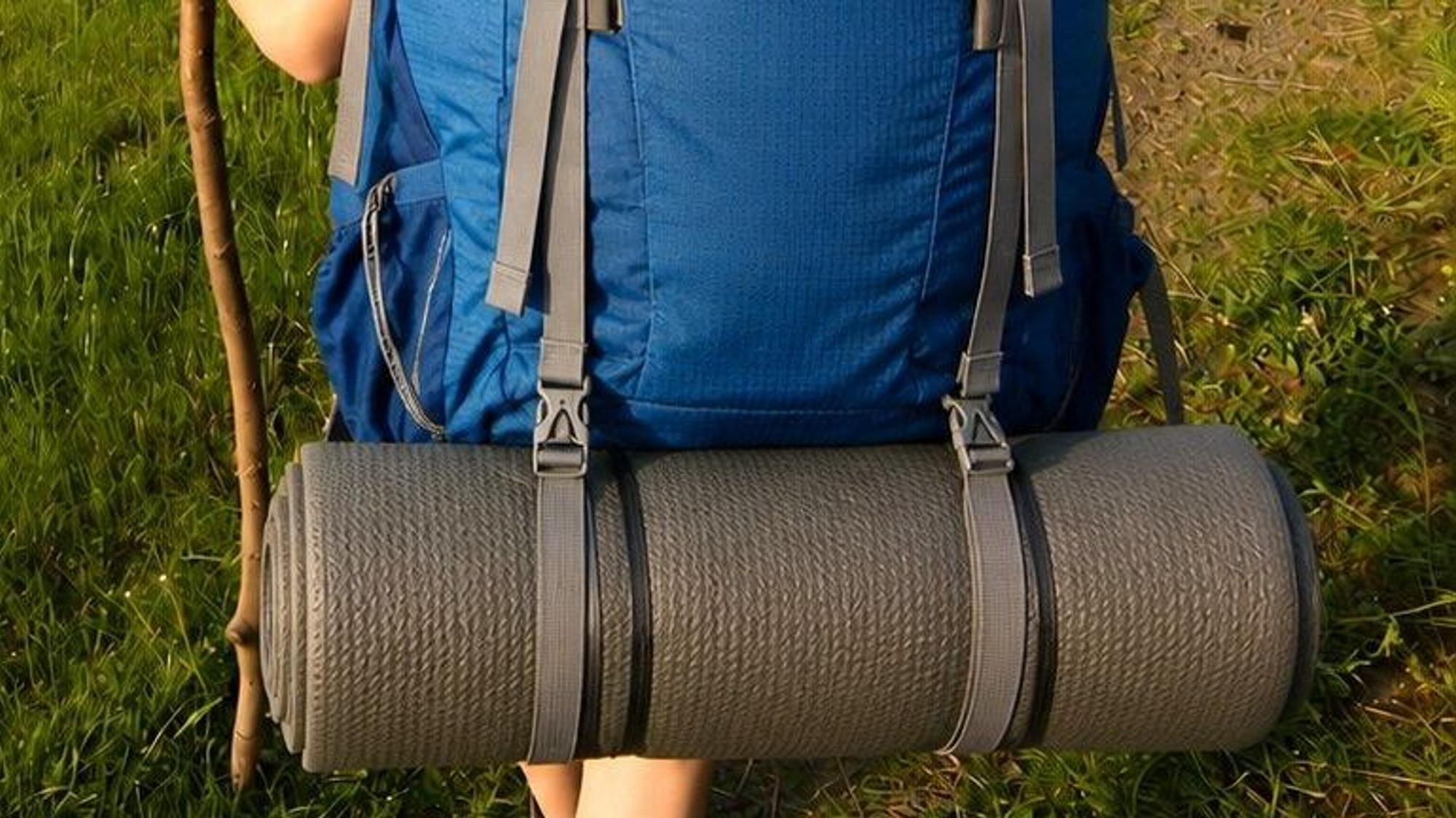 Eine blaue Isomatte hängt an einem grauen Rucksack.