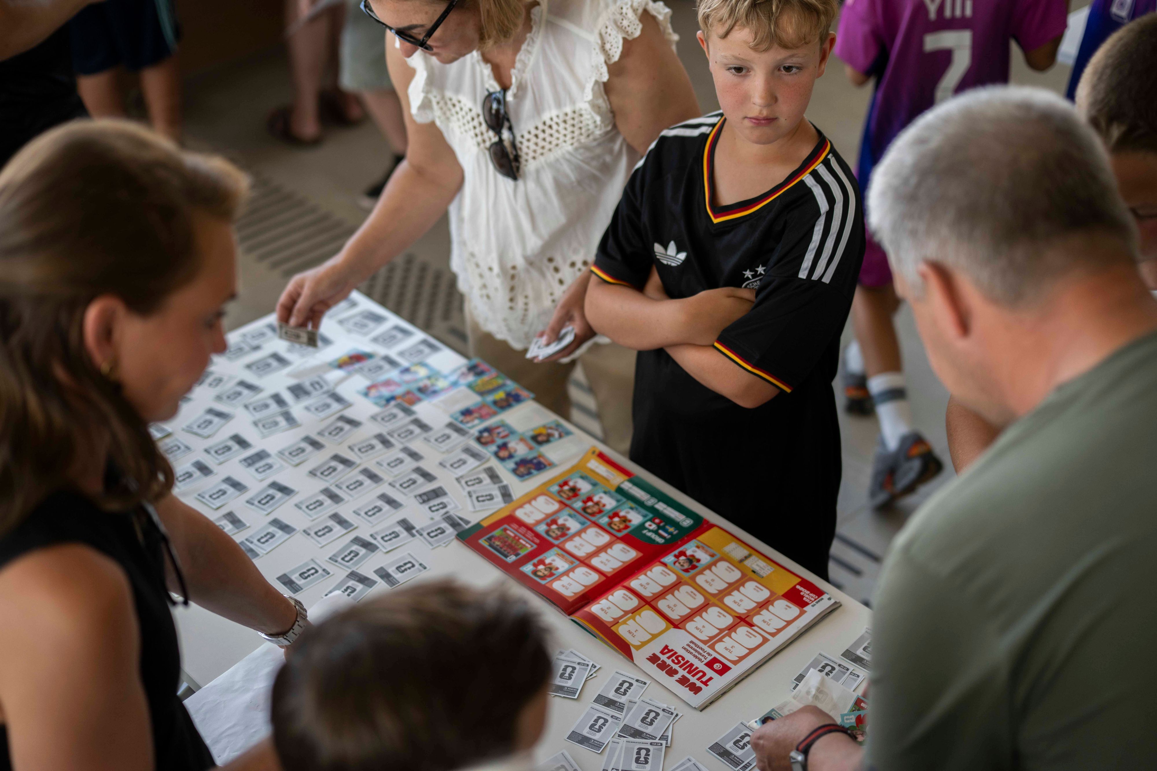Erwachsene und Kinder beugen sich über Sammelalben.