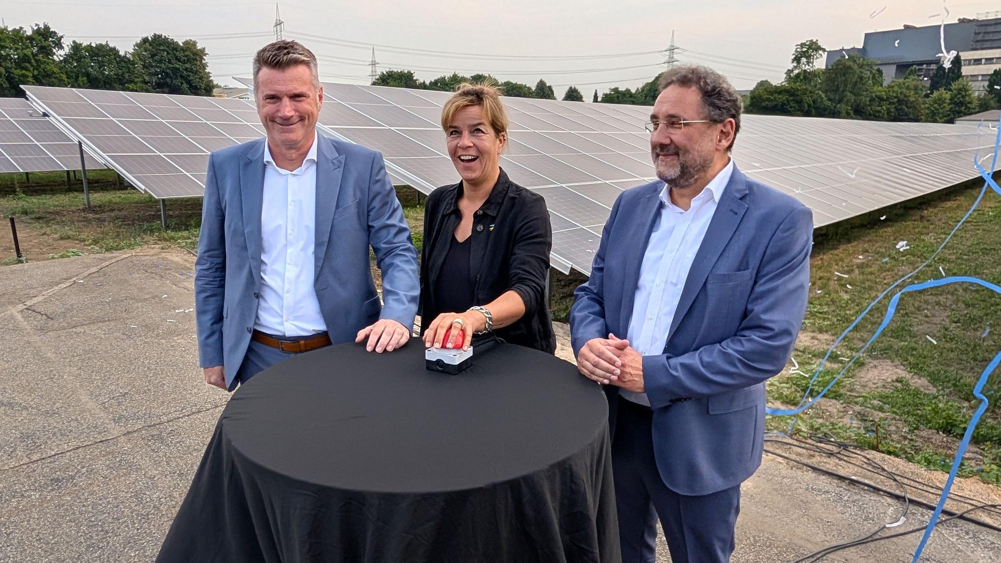 Das Foto zeigt die Geschäftsführer und die Ministerin beim symbolischen Knopfdruck vor einem Teil der Solarmodule.