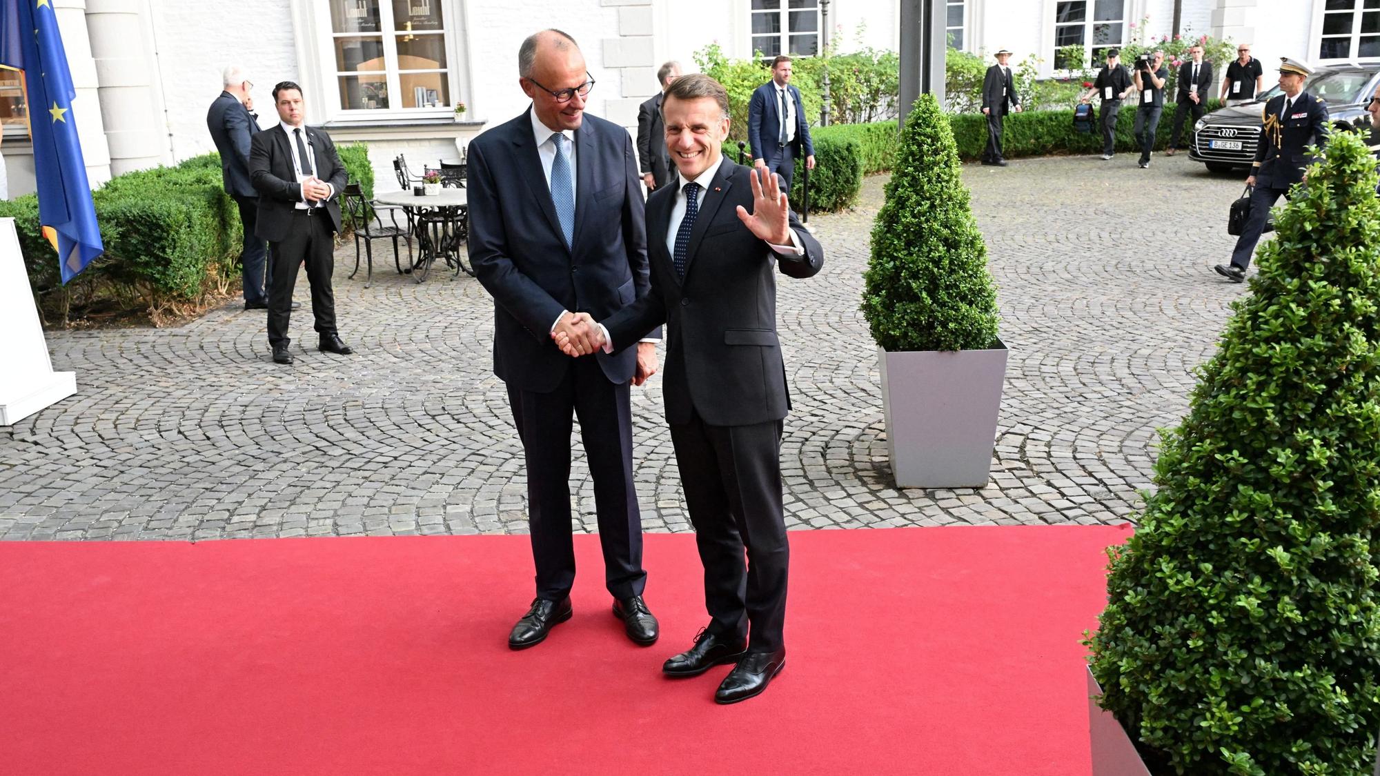 Friedrich Merz Merz und Emmanuel Macron reichen sich die Hand.