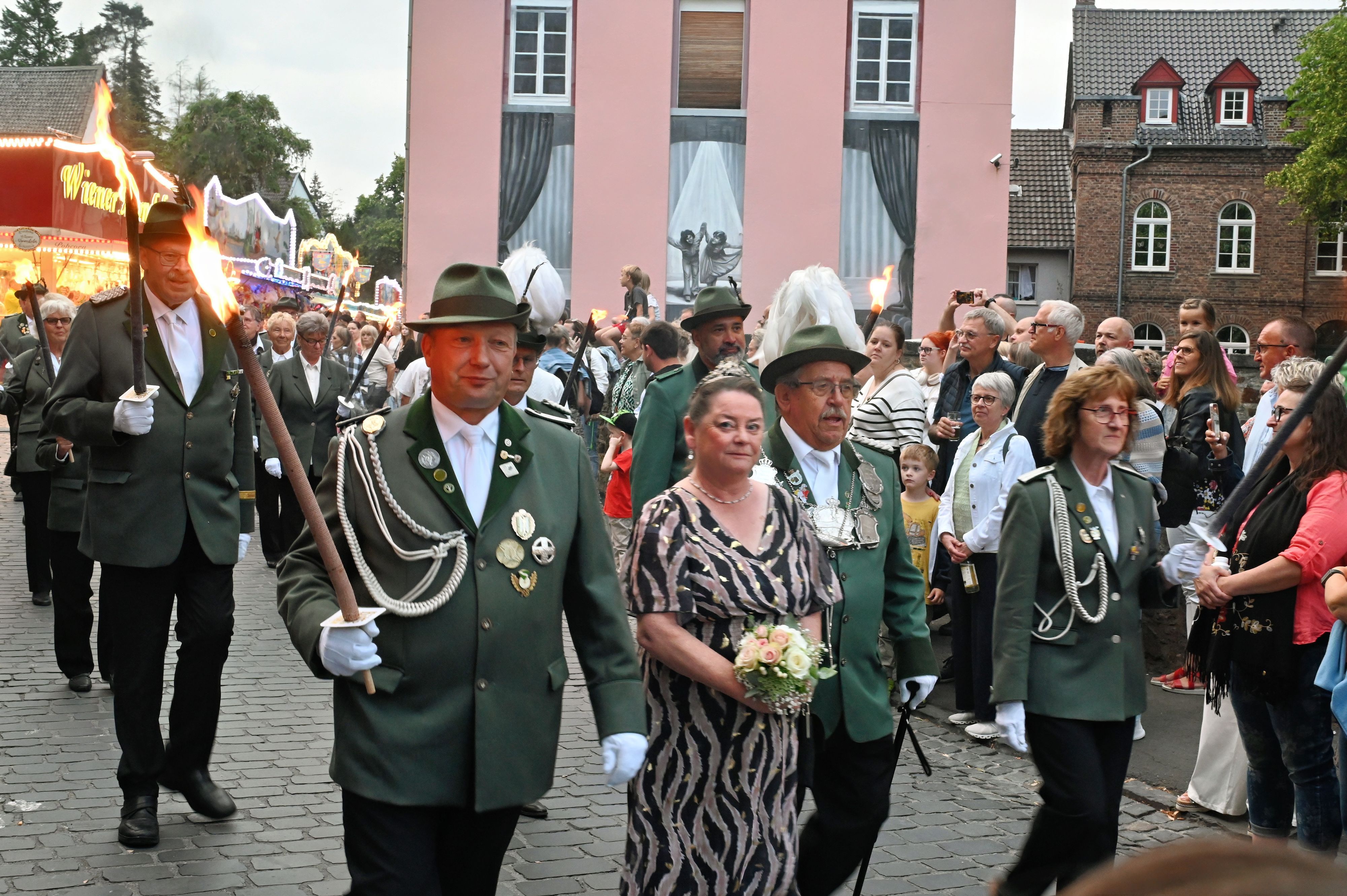 Schützen in Uniform und mit Fackeln marschieren durch die Stadt.