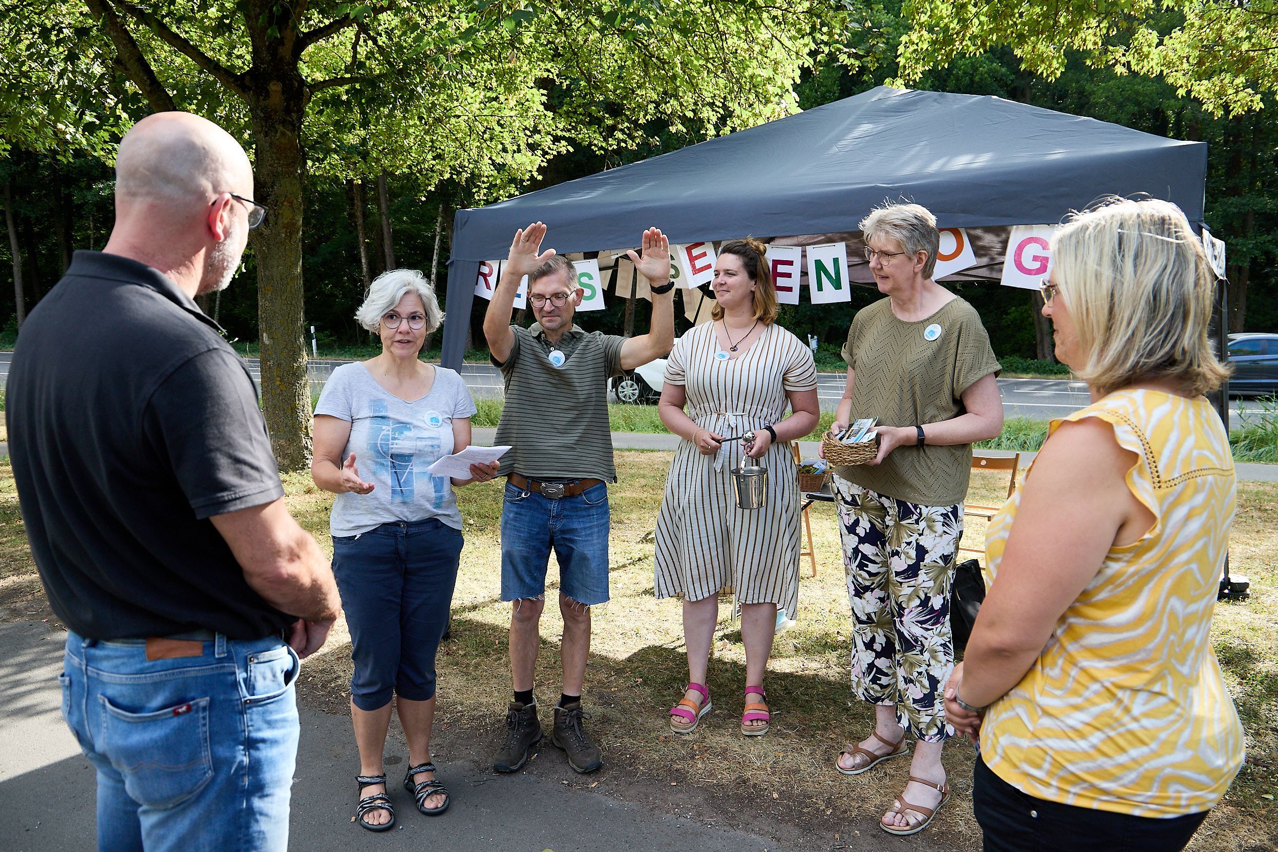 Antje und Günter Schmitz stehen rechts und links im Bild, in der Mitte sind die vier Segnenden zu sehen. Ein Mann hebt beide Hände.