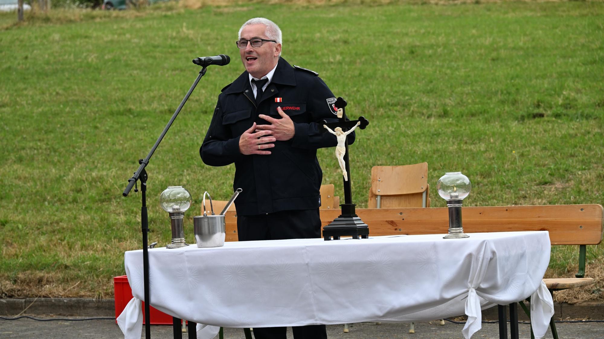 Eine Mann steht, die Hand auf die Brust gelegt, vor einem Mikrofon und redet.