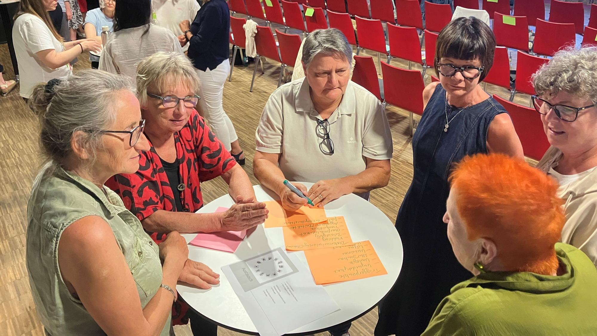 In einer Arbeitsgruppe tauschen sich sechs Teilnehmerinnen eines Workshop an einem Stehtisch untereinander aus.